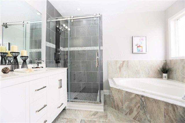 A beautifully remodeled bathroom featuring a frameless glass shower, sleek white vanity, and neutral tile design. Perfect inspiration for a modern home renovation in the Greater Toronto Area.