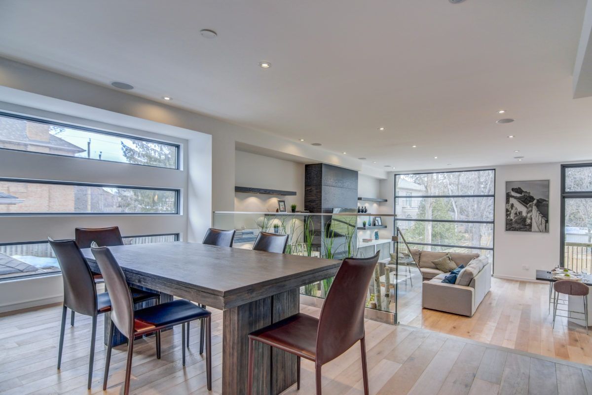 Modern open-concept dining and living space in a Toronto luxury home renovation featuring large windows, natural wood flooring, recessed pot lights, and contemporary furniture. The spacious layout connects dining, kitchen, and living areas seamlessly, creating a bright and elegant family living environment. Designed and renovated by a professional Toronto renovation company, this interior showcases modern design, comfort, and functional living.