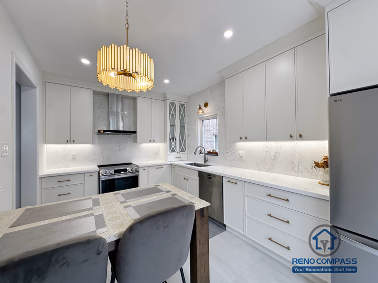 This Markham kitchen renovation features a refined, functional layout with custom white cabinetry, quartz countertops, and integrated under-cabinet lighting. The U-shaped workspace is designed for efficient daily use, while the central dining island creates a natural gathering point for family and guests. Gold-accent pendant lighting adds warmth and visual focus, complementing the clean finishes and modern appliances. The overall design balances practicality and elegance, delivering a bright, timeless kitchen tailored to contemporary living in Markham.