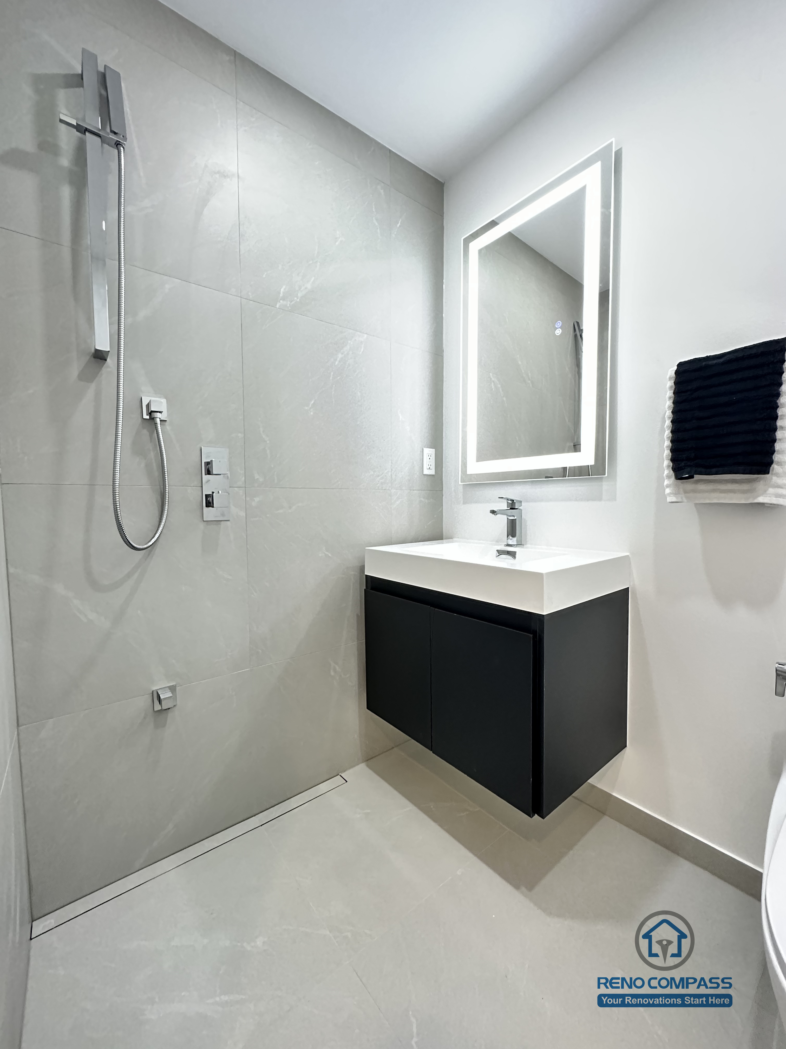 This image features a clean and modern accessible bathroom layout in Brampton, highlighting a floating vanity, integrated LED mirror, and a compact toilet designed for efficient space use. The wall-mounted vanity improves floor clearance, making the bathroom easier to clean and more accessible for daily use and pet care. Neutral-toned tiles and minimal fixtures create a calm, functional environment suitable for barrier-free living. This thoughtfully planned bathroom renovation was completed by an experienced Toronto Renovation Company specializing in accessible and pet-friendly home solutions.
