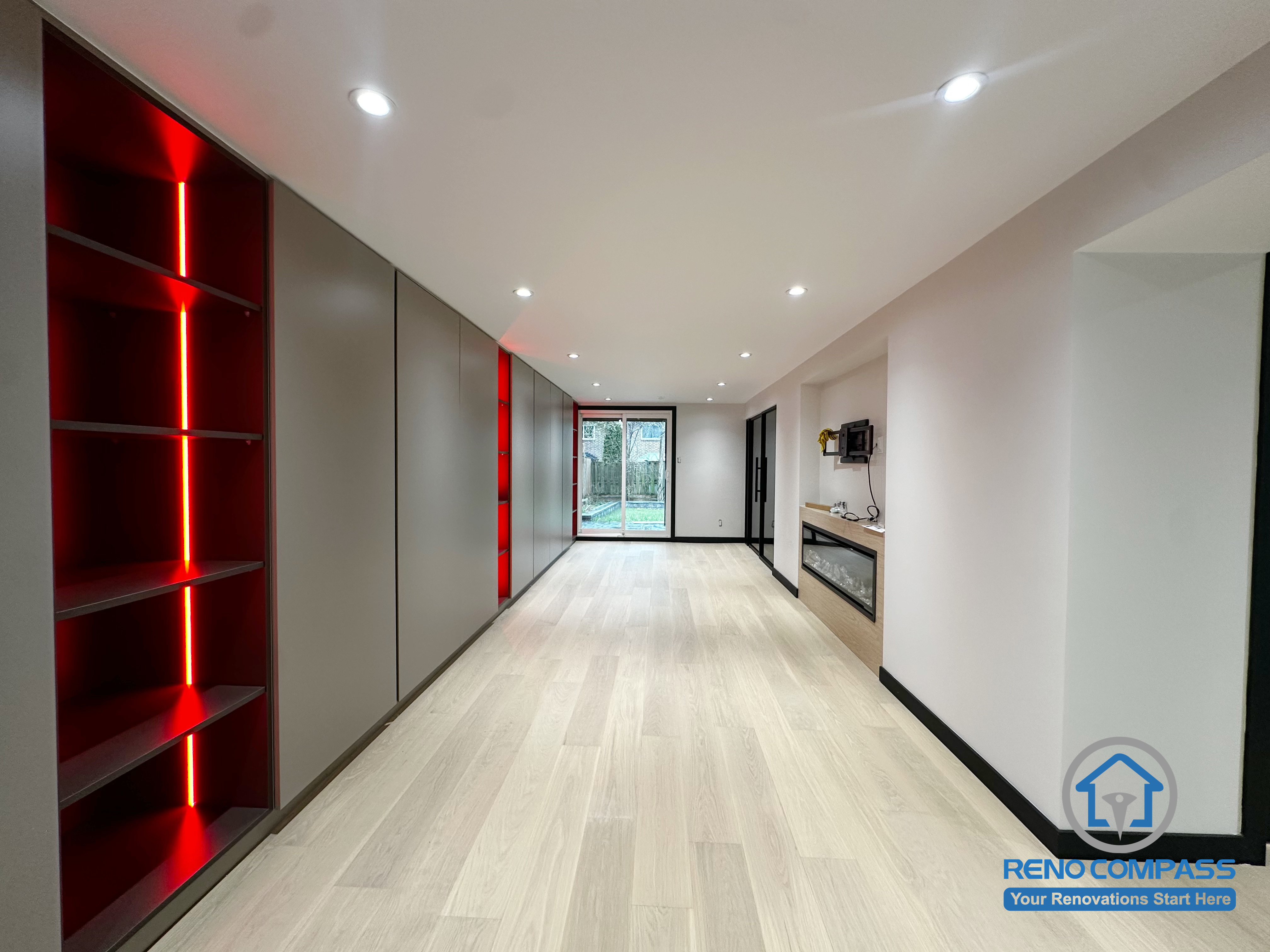 This Richmond Hill basement renovation features a striking LED-lit storage and display wall, adding depth, ambiance, and a modern touch to the space.
The light wood flooring brightens the entire basement, while the right-side built-in fireplace and media area create a cozy and versatile lounge perfect for entertainment, workouts, or family gatherings.

A clean, modern style combined with smart lighting makes this basement feel just as functional and comfortable as the main living floors.