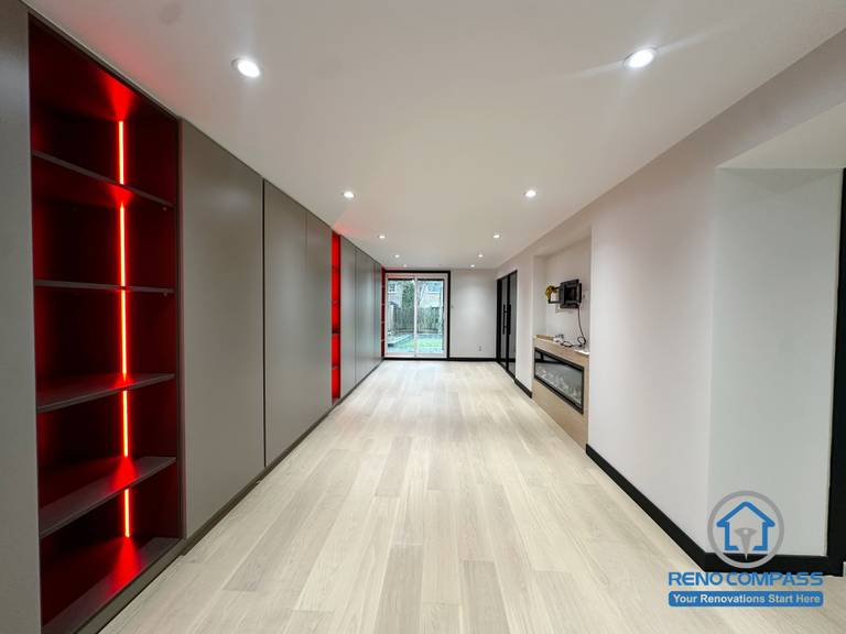 This Richmond Hill basement renovation features a striking LED-lit storage and display wall, adding depth, ambiance, and a modern touch to the space.
The light wood flooring brightens the entire basement, while the right-side built-in fireplace and media area create a cozy and versatile lounge perfect for entertainment, workouts, or family gatherings.

A clean, modern style combined with smart lighting makes this basement feel just as functional and comfortable as the main living floors.