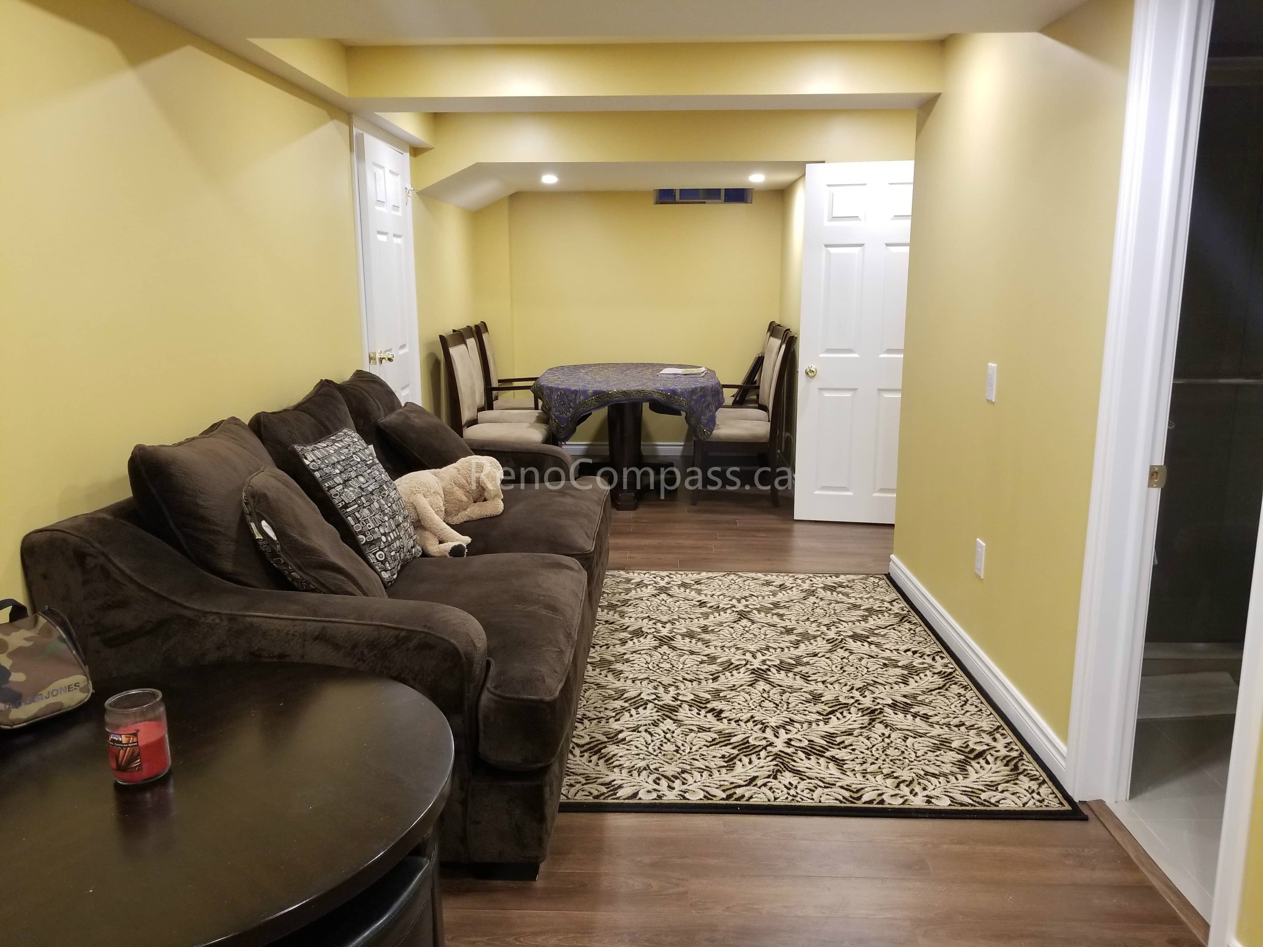 This Vaughan basement renovation showcases a fully finished living and dining area with durable wood-look flooring, recessed pot lights, and a warm modern color palette. The open layout creates a comfortable multi-functional space ideal for family gatherings, relaxation, or entertainment. Completed by Reno Compass Inc., this basement transformation enhances usability, lighting, and overall home value with a clean and inviting design.