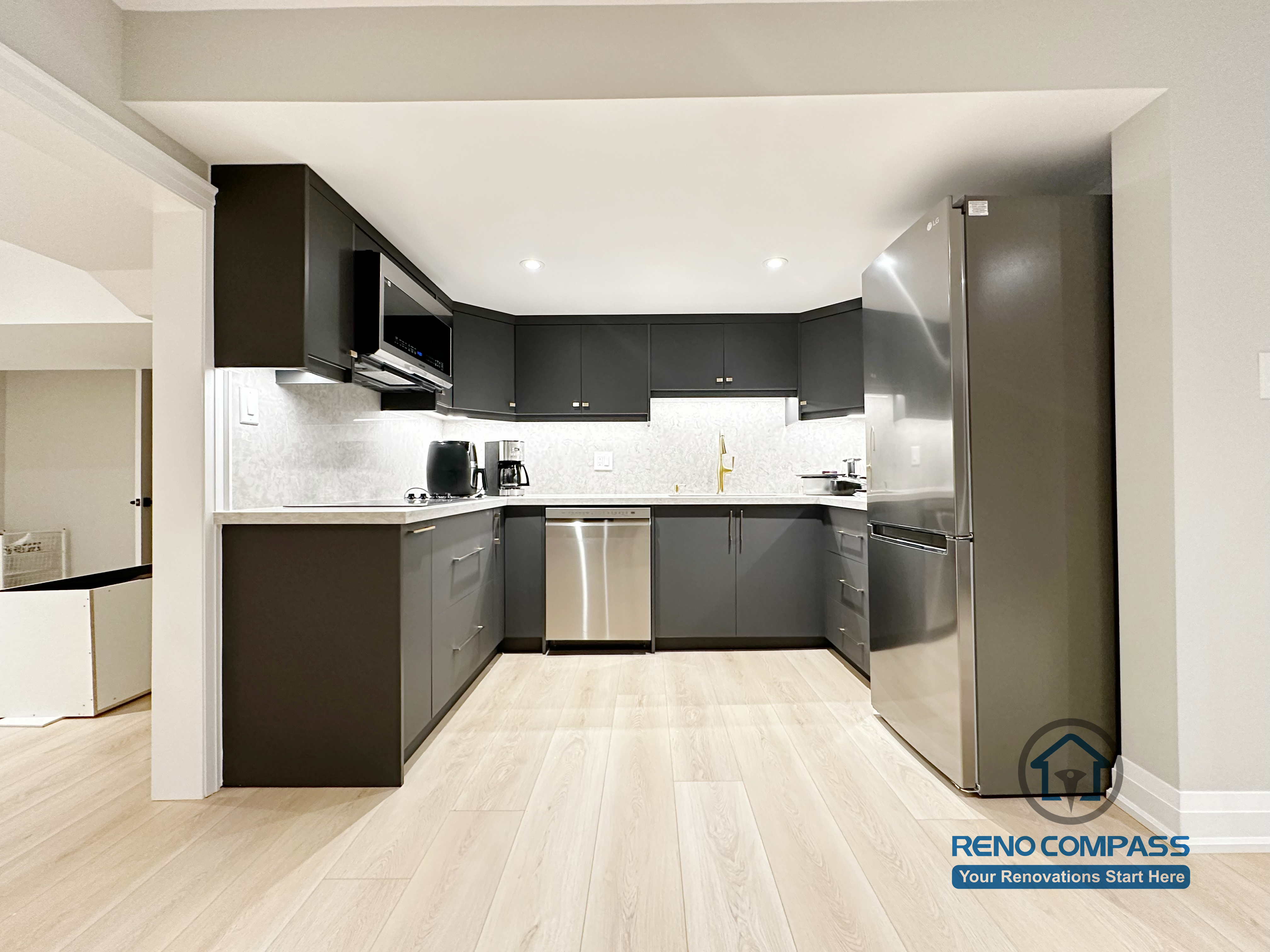 Basement renovation in Richmond Hill featuring a modern kitchenette with matte black cabinetry, stainless steel appliances, quartz-style countertops, and efficient space planning for daily use.