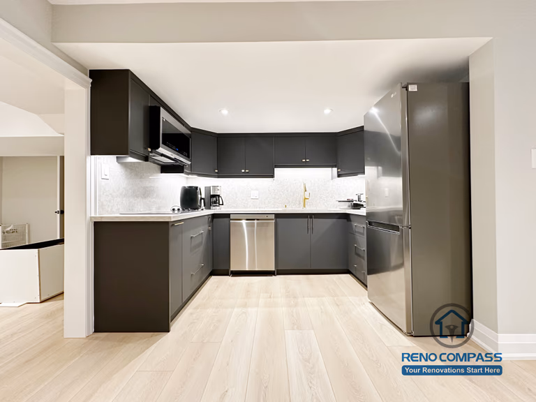 Basement renovation in Richmond Hill featuring a modern kitchenette with matte black cabinetry, stainless steel appliances, quartz-style countertops, and efficient space planning for daily use.