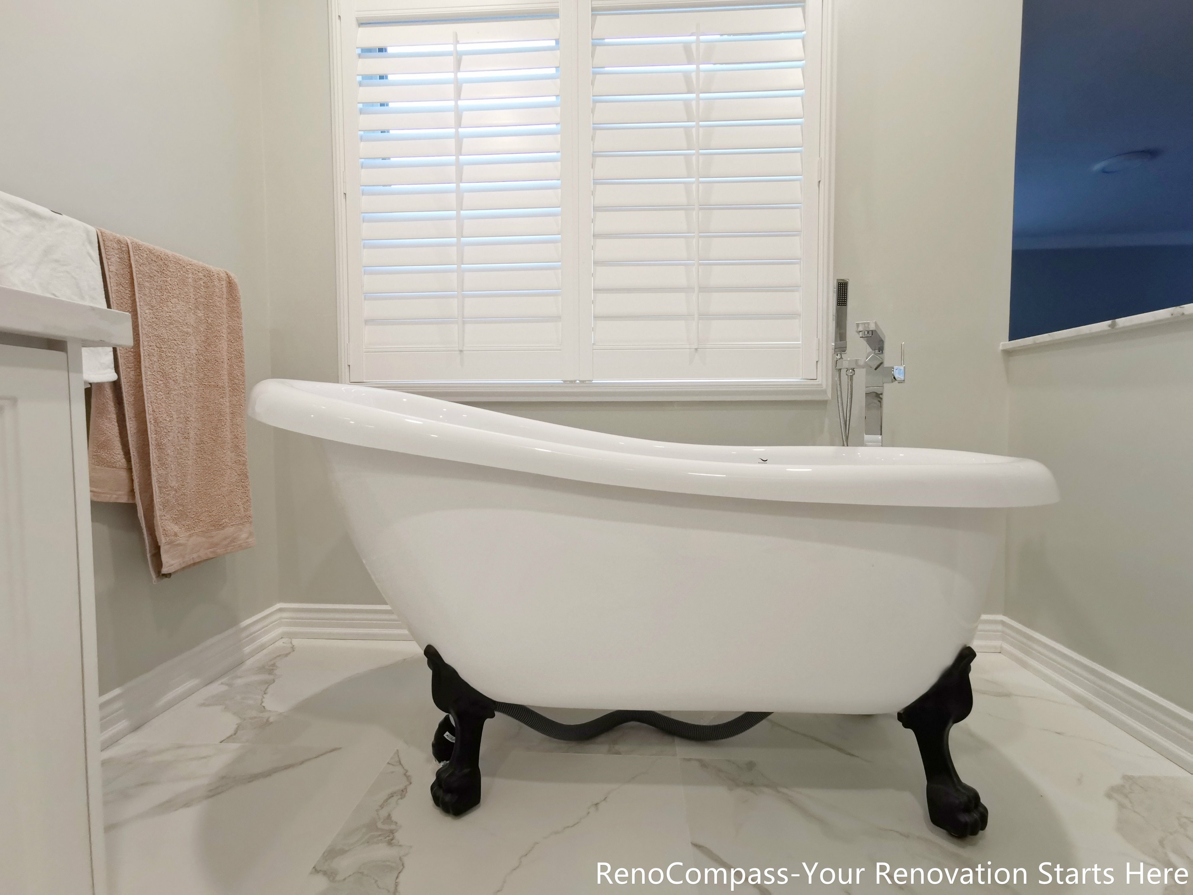 This image highlights a freestanding bathtub featured in an Oakville bathroom renovation. The sculptural tub sits on polished marble flooring, creating a clean and elegant focal point within the space. Soft natural light from the window enhances the bright, calming atmosphere, while the classic tub design paired with refined finishes adds a timeless, spa-inspired feel. The overall layout emphasizes comfort, balance, and understated luxury suitable for long-term everyday living.