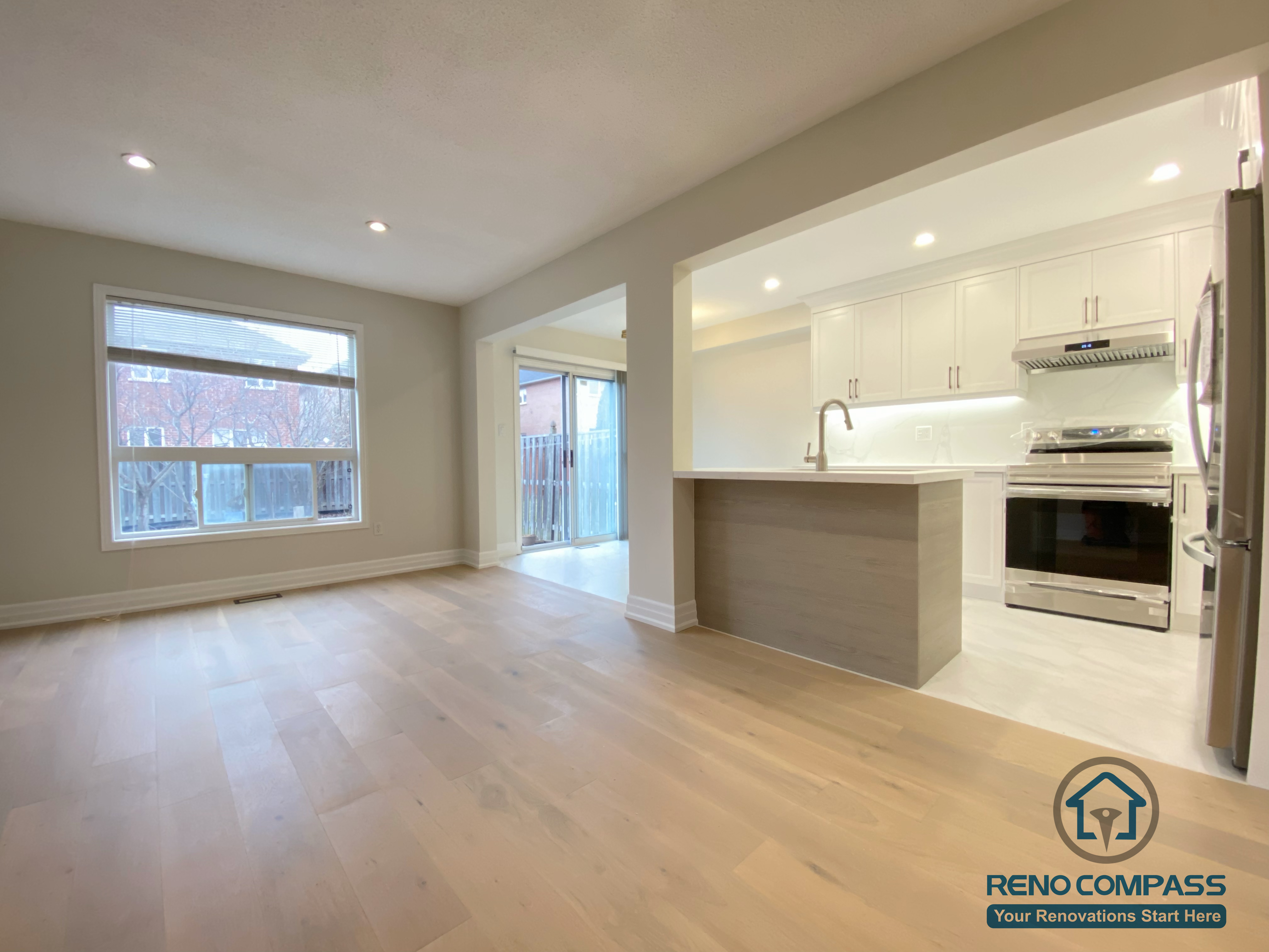 This Markham interior renovation features a bright open-concept living and kitchen space designed for modern family living. Wide-plank hardwood flooring, large windows, and recessed ceiling lights create an airy and welcoming atmosphere. The kitchen is seamlessly integrated with the living area, showcasing white cabinetry, quartz countertops, and a functional island that enhances daily use and entertaining. Completed by a professional Toronto renovation company, this renovation improves natural light, spatial flow, and overall comfort for a Markham home.