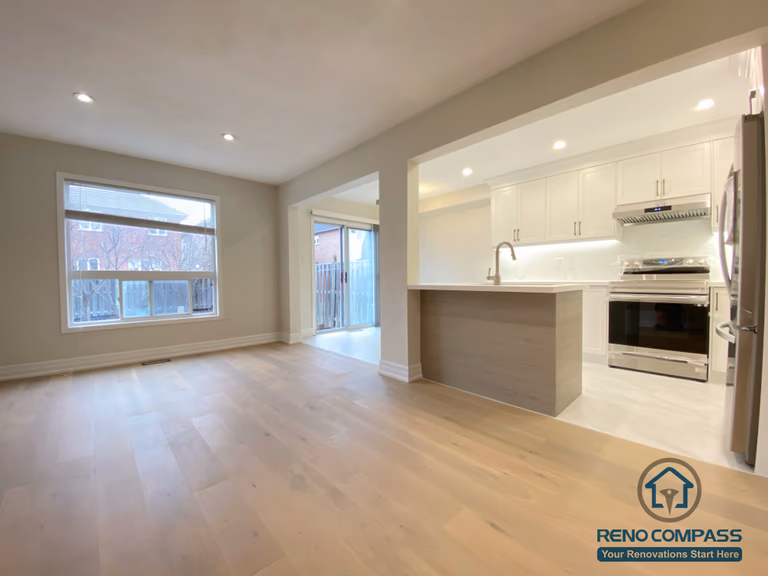 This Markham interior renovation features a bright open-concept living and kitchen space designed for modern family living. Wide-plank hardwood flooring, large windows, and recessed ceiling lights create an airy and welcoming atmosphere. The kitchen is seamlessly integrated with the living area, showcasing white cabinetry, quartz countertops, and a functional island that enhances daily use and entertaining. Completed by a professional Toronto renovation company, this renovation improves natural light, spatial flow, and overall comfort for a Markham home.