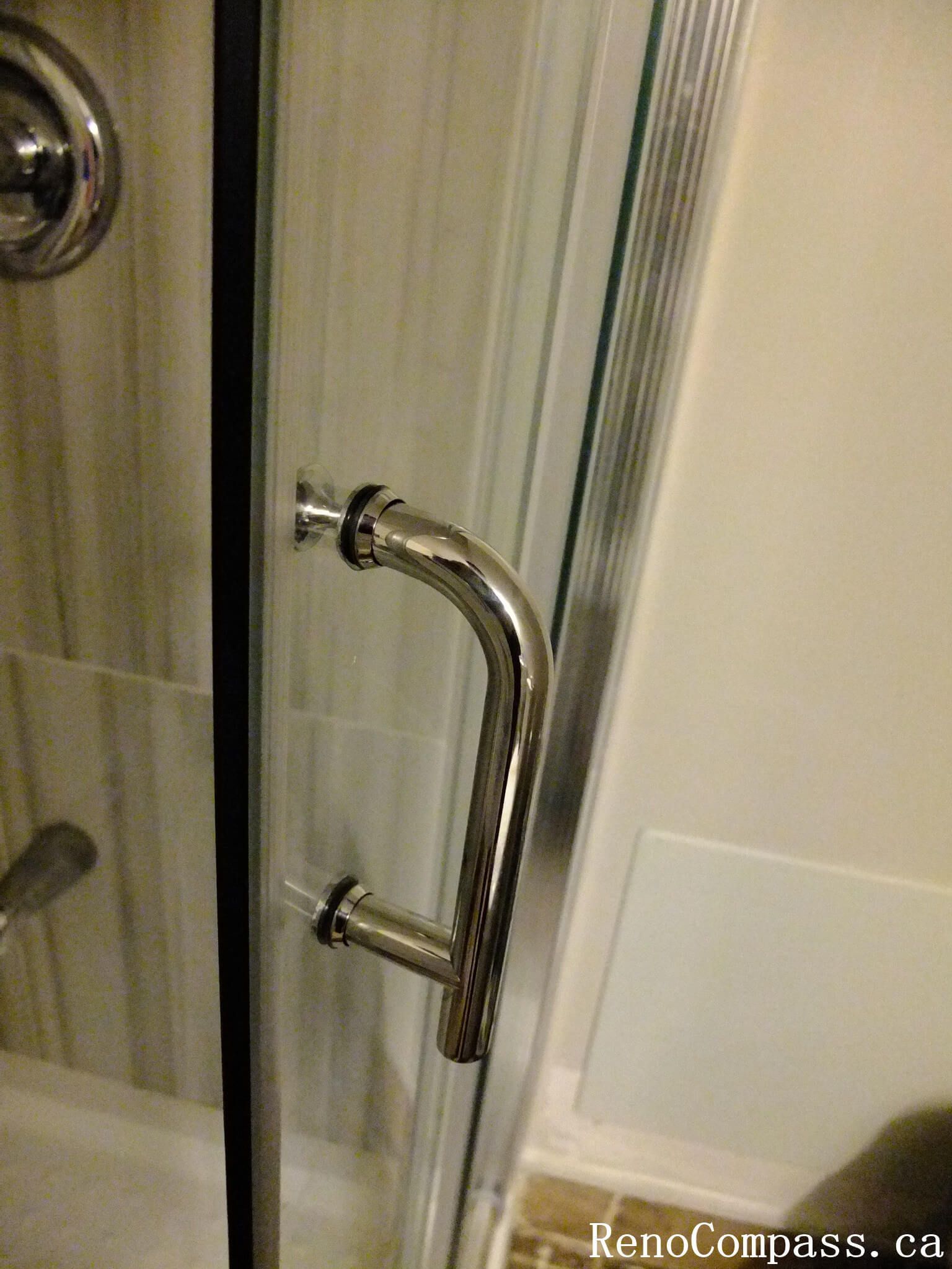 Glass shower door handle detail from a North York bathroom renovation, featuring a polished chrome handle and clean glass installation for a durable and functional shower enclosure.