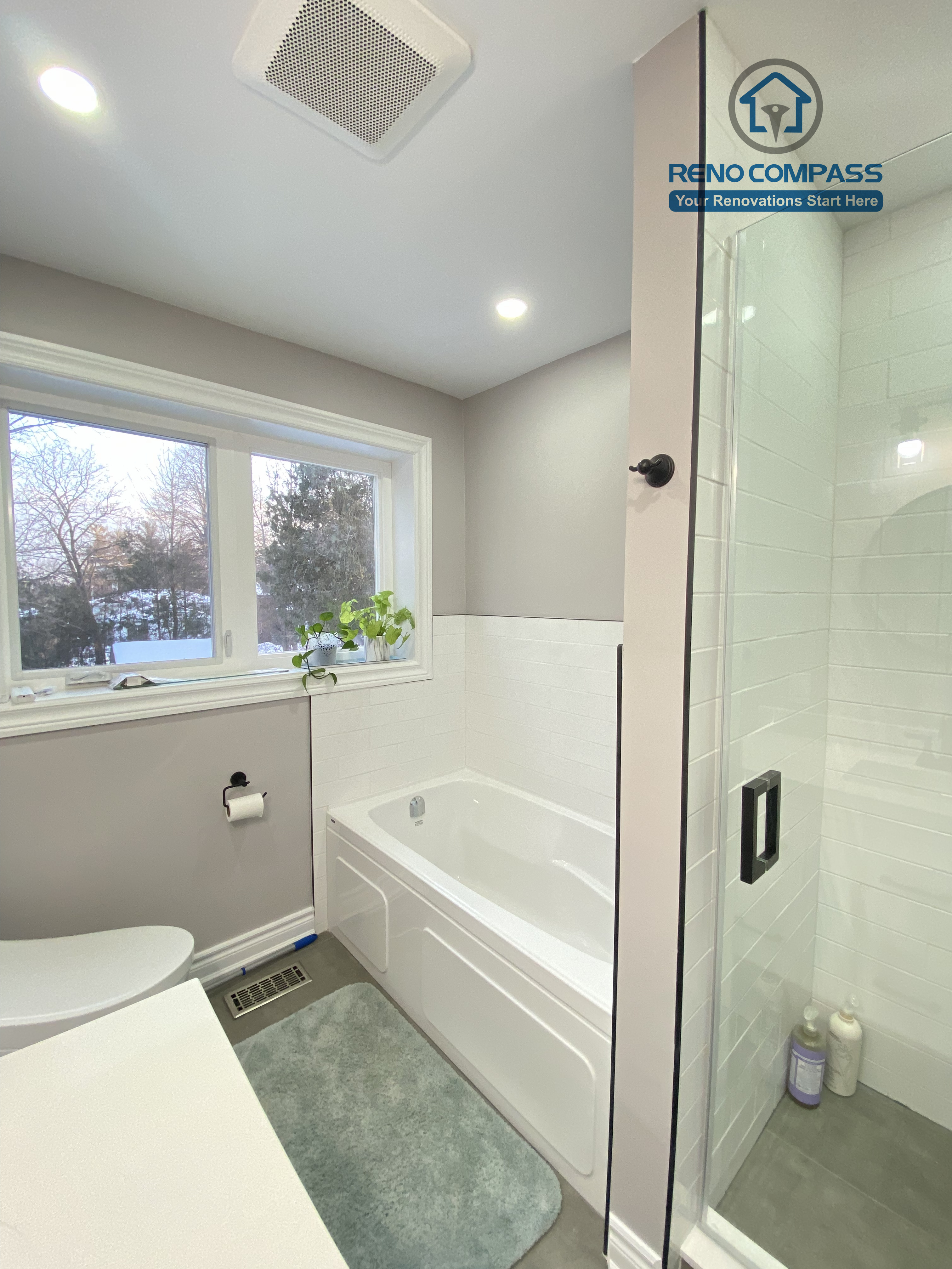 This North York bathroom renovation presents a bright and well-organized layout featuring a built-in bathtub, a glass-enclosed shower, and recessed ceiling lighting. Natural light from the window enhances the soft gray and white color palette, creating a clean and comfortable bathroom space completed by a Toronto renovation company with a focus on practical design and quality execution.
