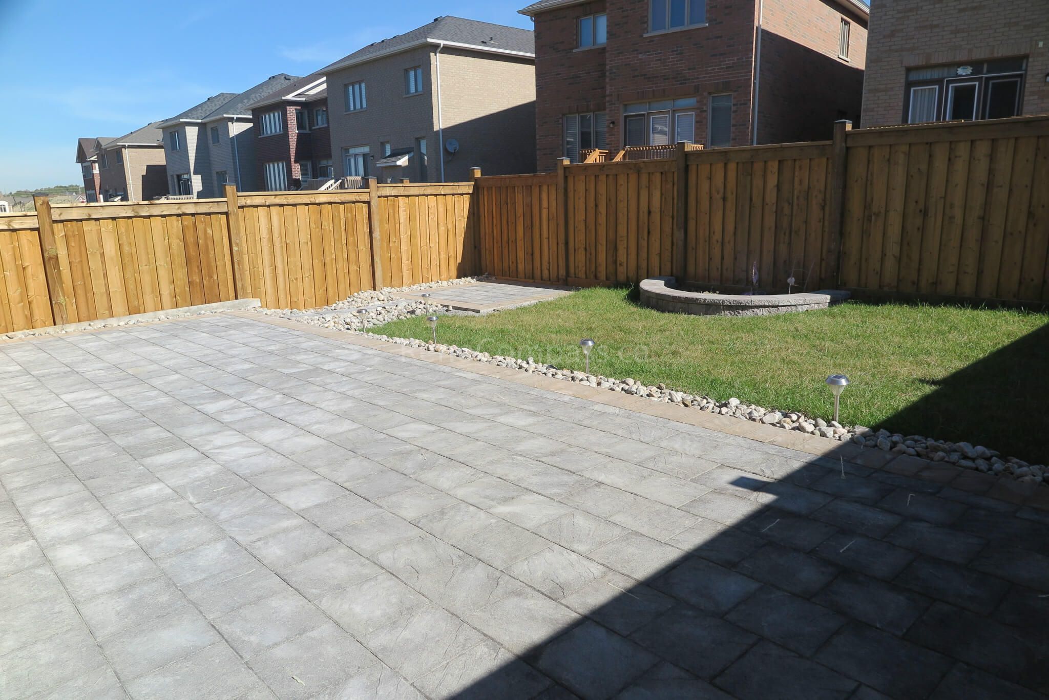Modern backyard interlocking patio installation in Aurora featuring grey stone pavers, custom front steps, and clean edge detailing along the brick exterior. This professional landscaping and paving project creates a durable, elegant outdoor living and entrance area with a low-maintenance design. Completed by Reno Compass Inc., a trusted Toronto renovation and landscaping contractor serving Aurora and the GTA.