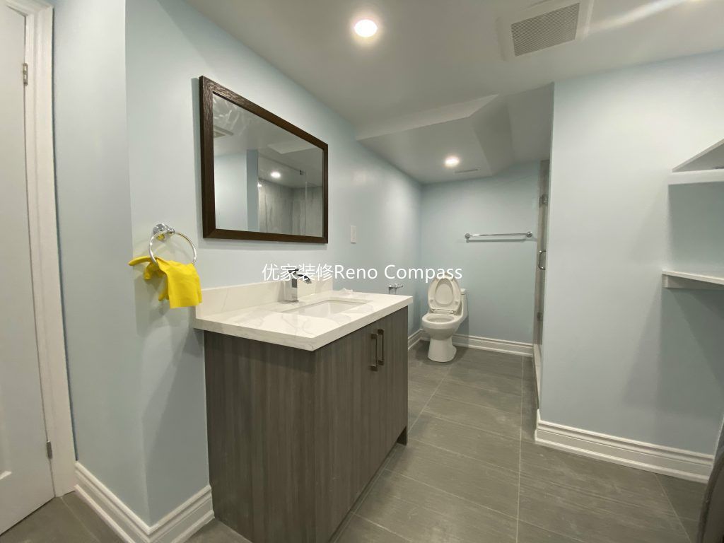 This Aurora basement renovation includes a modern bathroom and laundry area upgrade completed by a professional Toronto renovation company. The space features a sleek vanity with quartz countertop, contemporary tile flooring, glass walk-in shower, and a dedicated washer and dryer setup with custom shelving for efficient storage. Bright LED pot lights and soft neutral tones enhance the clean and functional layout, transforming the basement into a fully equipped and comfortable living space. Contractor: Reno Compass Inc.