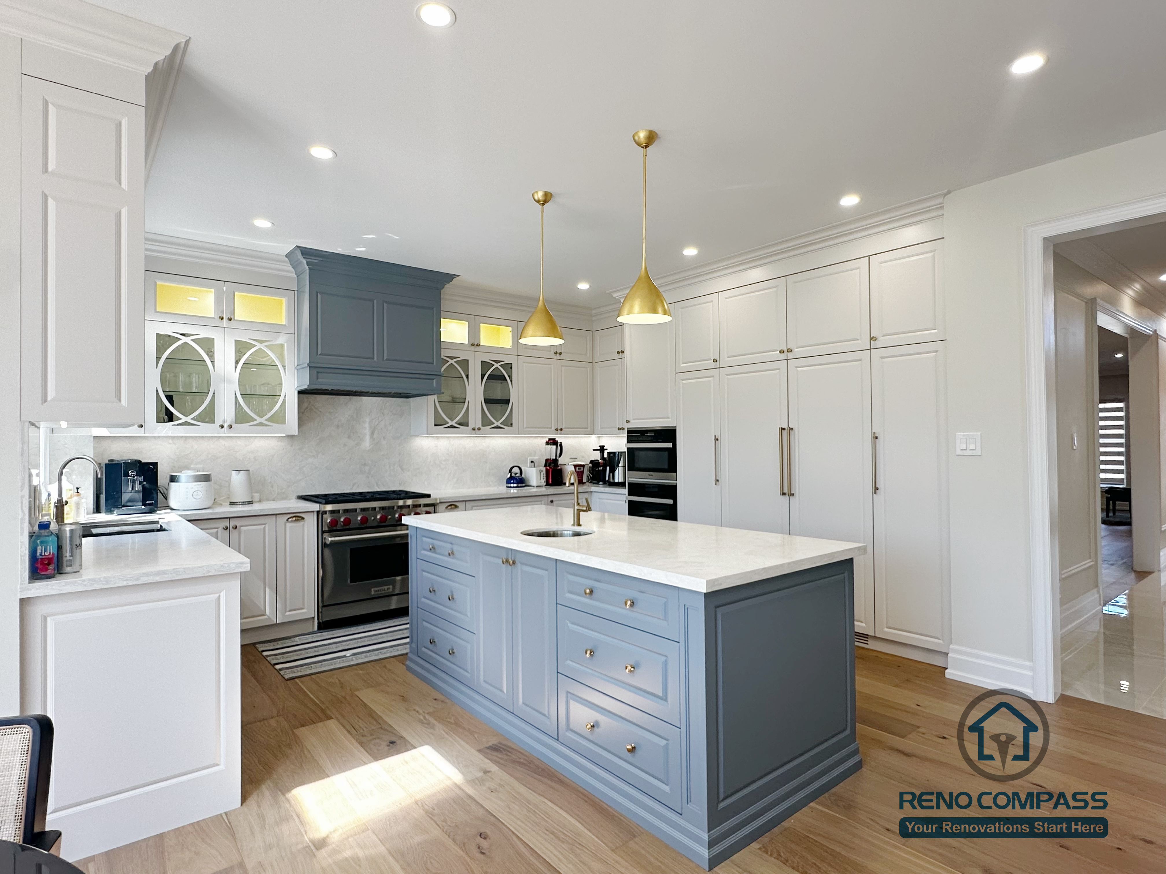 This North York kitchen renovation highlights a custom blue island with integrated drawers, full-height built-in cabinetry, and balanced recessed and pendant lighting. The layout maximizes storage efficiency while maintaining clean lines and visual symmetry, creating a refined and highly functional kitchen space designed and built by Reno Compass.