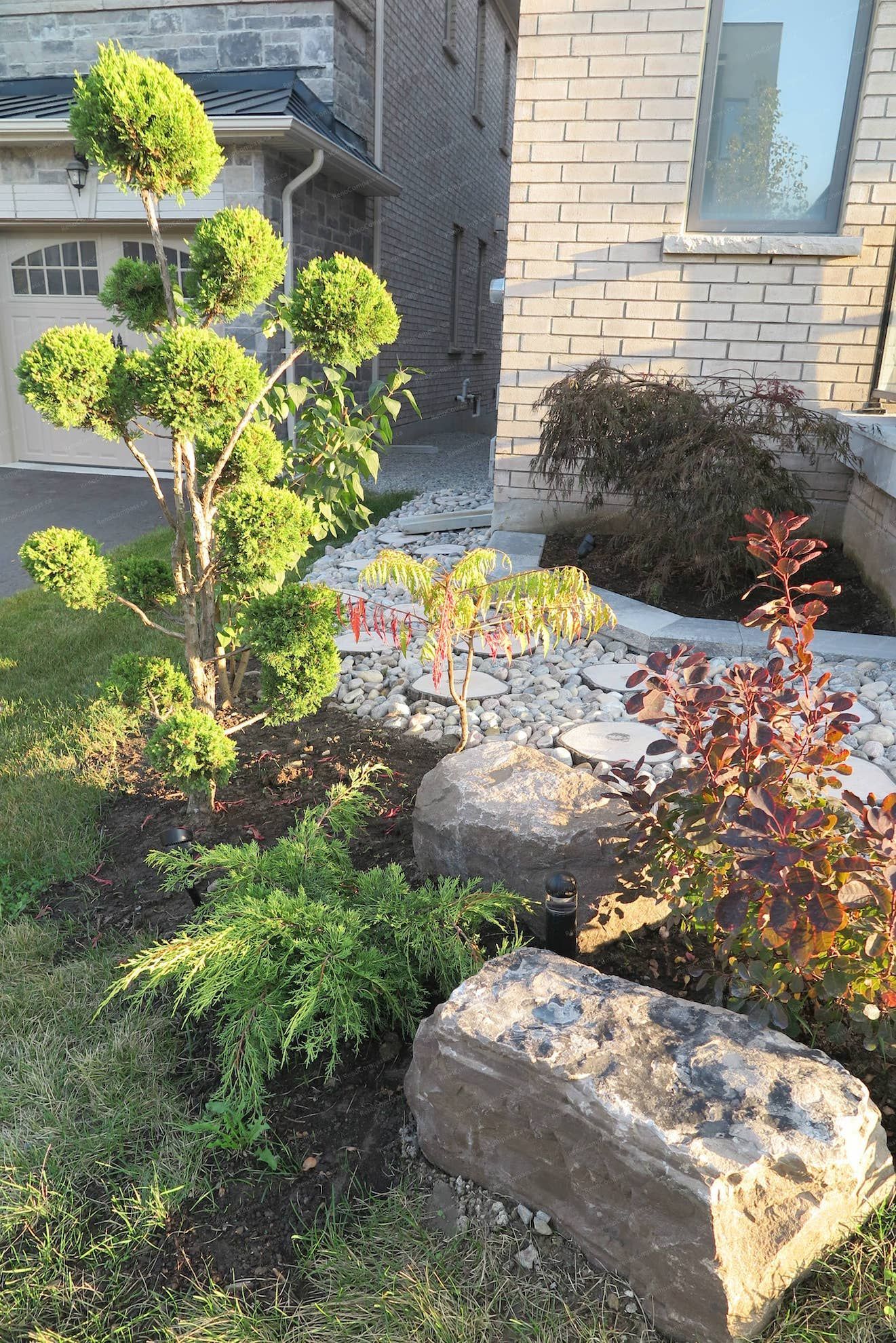This Vaughan landscaping renovation highlights a beautifully designed front yard with decorative stone landscaping, sculpted greenery, and a modern pathway leading to the home entrance. The project enhances curb appeal while creating a clean, elegant outdoor space that complements the home’s architectural style. Professionally completed by Reno Compass Inc. 🌿🏡