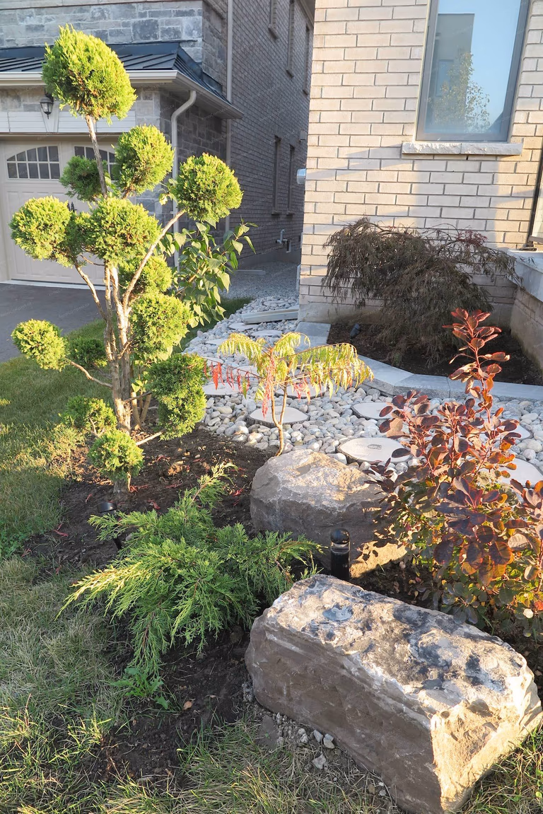 This Vaughan landscaping renovation highlights a beautifully designed front yard with decorative stone landscaping, sculpted greenery, and a modern pathway leading to the home entrance. The project enhances curb appeal while creating a clean, elegant outdoor space that complements the home’s architectural style. Professionally completed by Reno Compass Inc. 🌿🏡