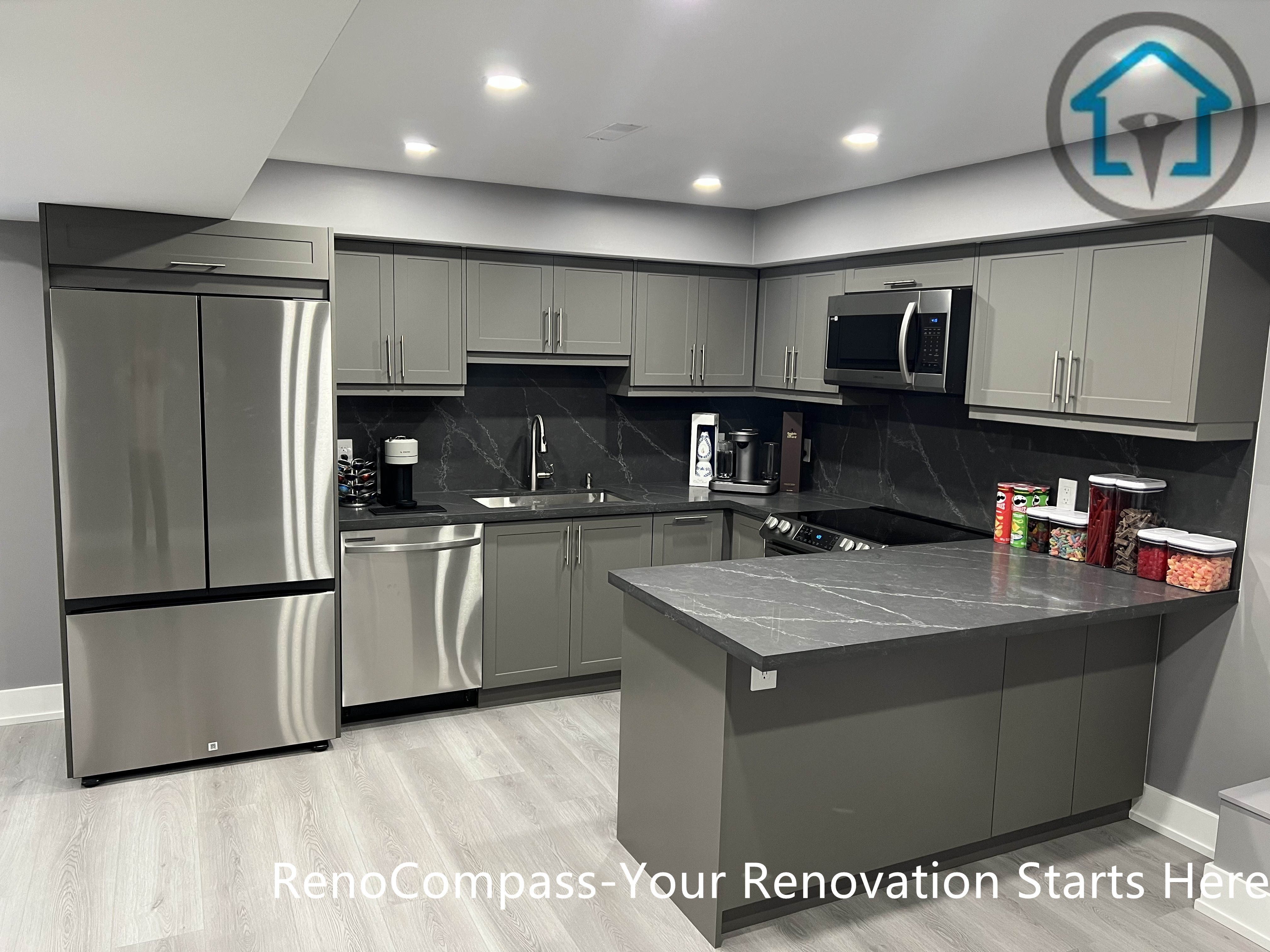 This Vaughan basement renovation highlights a modern kitchen featuring custom gray cabinetry, a central island with stone-look countertop, stainless steel appliances, and recessed ceiling lighting. The functional layout maximizes storage and workspace while maintaining a clean, contemporary appearance suitable for basement living. Completed by a Toronto renovation company, this basement kitchen renovation demonstrates practical design, durable materials, and efficient use of space.