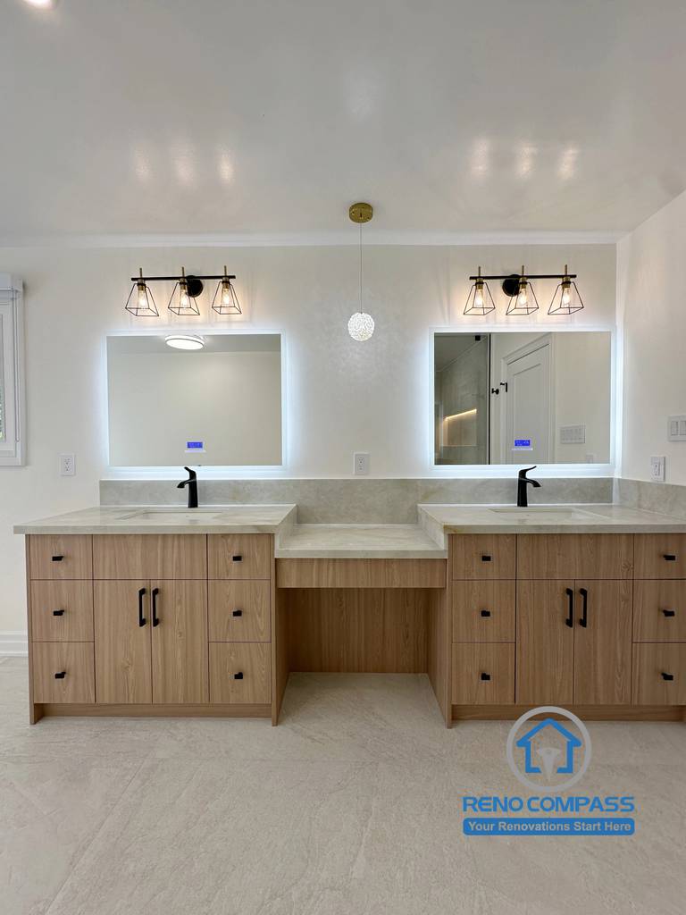 A luxury primary bathroom featuring a custom double vanity, integrated makeup station, quartz countertops, LED backlit mirrors, matte black faucets, and custom wood cabinetry. Completed as part of a whole home renovation in Markham, Ontario, this modern bathroom combines elegant storage, everyday functionality, and premium craftsmanship by Reno Compass.