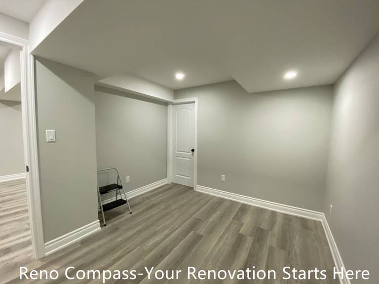This Aurora basement renovation includes a newly finished multi-purpose room designed to adapt to various needs such as a home office, guest room, or hobby space. The layout features clean wall lines, recessed ceiling lighting, and durable wood-look flooring to ensure long-term usability and comfort. Structural soffits are carefully integrated into the ceiling design to maintain a balanced visual proportion while maximizing headroom. Neutral finishes allow for easy customization, making this space a practical addition to a fully renovated basement completed by Reno Compass.
