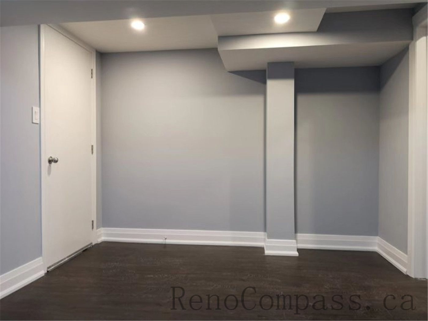 This modern basement renovation in Aurora highlights smooth light-gray walls, bright recessed lighting, and dark hardwood floors. The simple yet refined design adds warmth, depth, and functionality to the lower level — completed by Reno Compass.