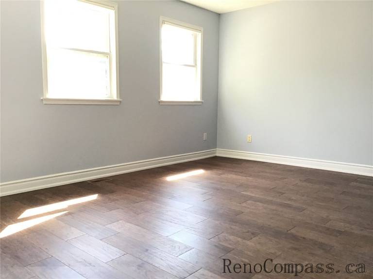 This image shows a renovated bedroom in Richmond Hill featuring warm-toned wood flooring and soft neutral wall colors. The clean baseboards and smooth finish create a cozy, modern living environment with enhanced durability.