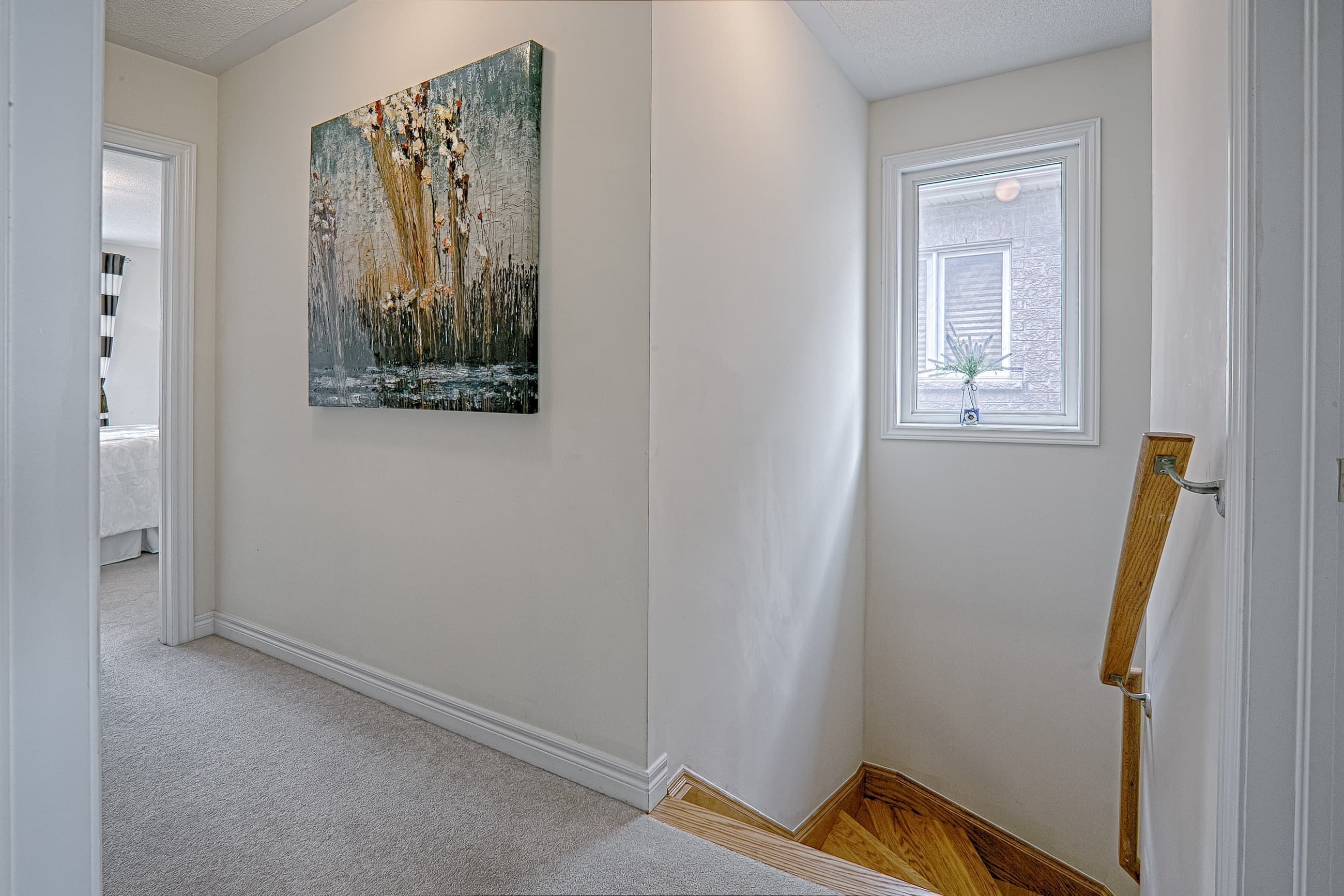 This upper floor landing renovation showcases a bright transitional space connecting bedrooms with a clean, neutral design. Soft carpeting enhances comfort, while natural light from the side window improves brightness and openness. The finished wooden stair edge detail adds warmth and craftsmanship to the transition between levels. Completed by a professional Toronto renovation company, this interior upgrade emphasizes smooth circulation, refined finishes, and cohesive modern residential design.