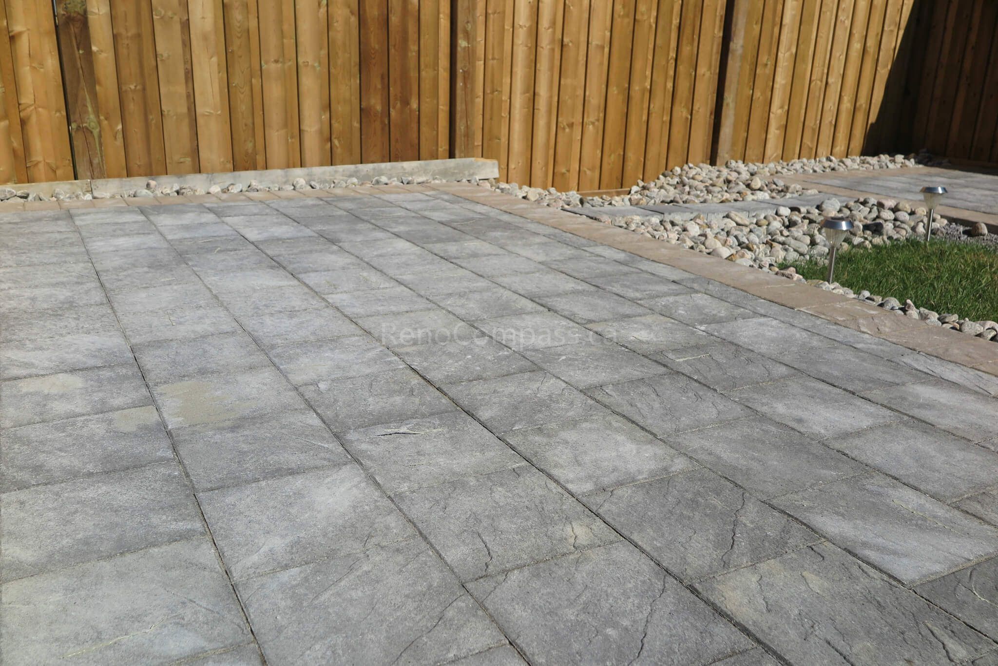 This Aurora landscaping project features a newly completed backyard design with professional interlocking stone installation, modern patio layout, and custom wood fencing. The clean grey paver pattern creates a spacious and durable outdoor living area, perfect for family use and entertaining. Completed by Reno Compass Inc., a trusted Toronto renovation and landscaping contractor serving Aurora and the GTA.