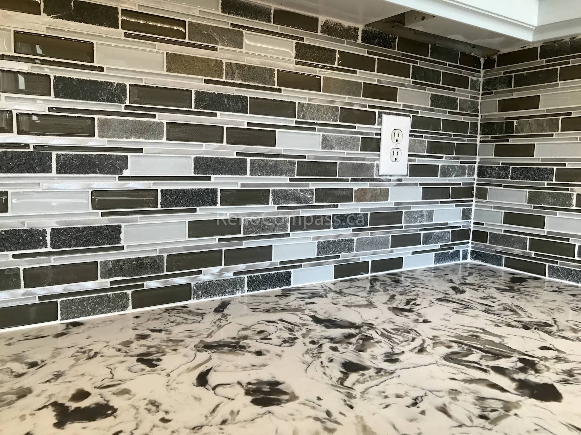 This close-up from a Markham kitchen renovation highlights the modern mosaic tile backsplash paired with a marble-pattern countertop. The layered tile design adds depth and texture, while clean grout lines and precise outlet placement reflect quality craftsmanship and attention to detail in this contemporary kitchen upgrade.