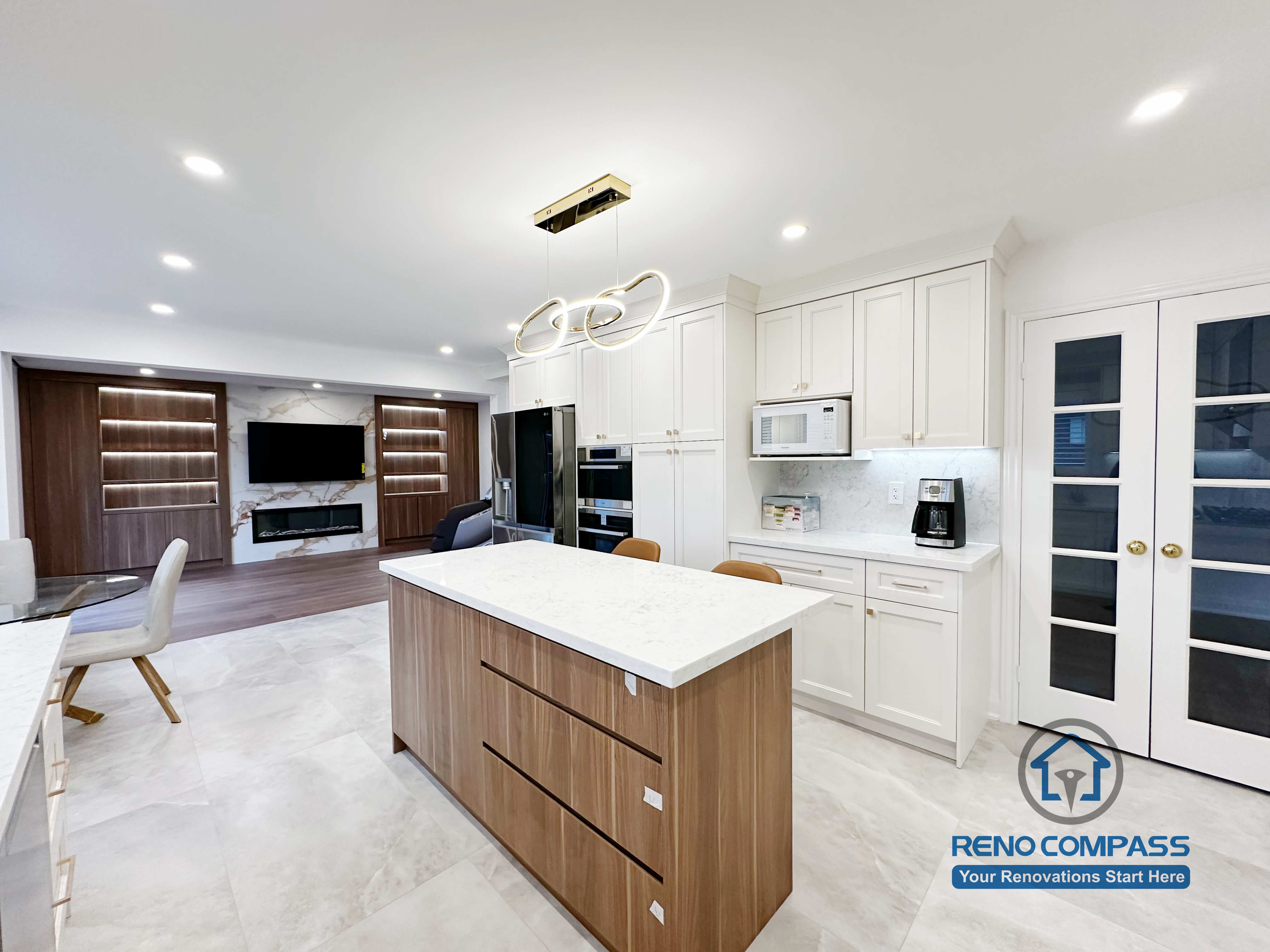 This Markham kitchen renovation showcases a spacious central island with quartz countertop, custom wood base cabinetry, and an open-concept layout that connects seamlessly to the living area. The design balances white perimeter cabinets with warm wood tones, improving both storage capacity and visual depth. Recessed lighting and modern pendant fixtures enhance overall brightness and functionality, making the kitchen ideal for daily cooking and entertaining.