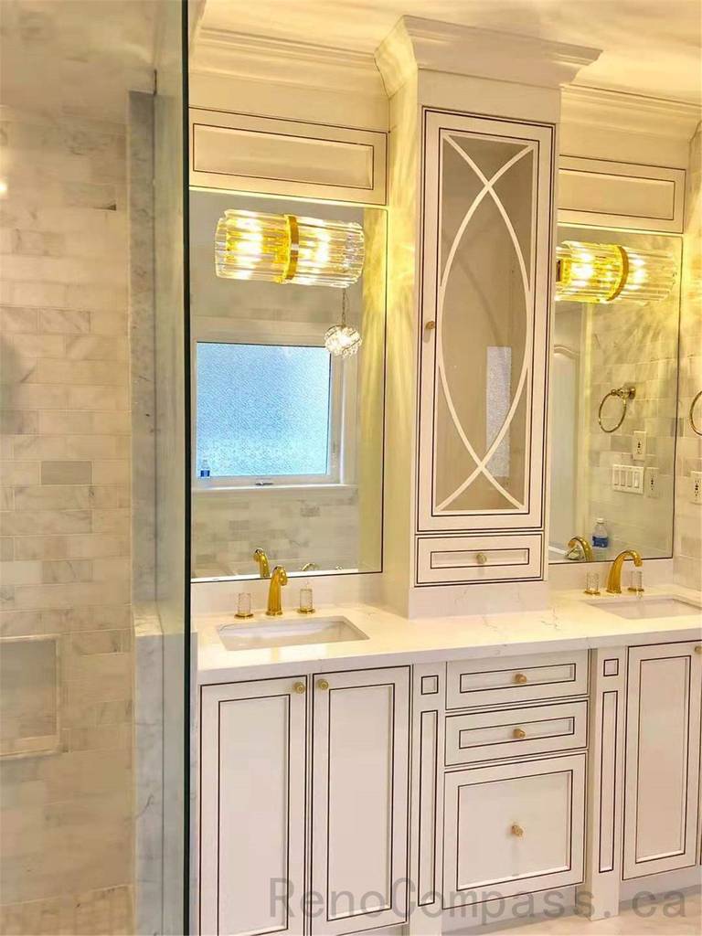 This North York bathroom renovation features a luxury double vanity with custom cabinetry, integrated storage, and elegant gold fixtures. Large mirrors, decorative wall panels, and layered lighting enhance brightness and symmetry, creating a refined and functional primary bathroom designed for comfort and daily use.