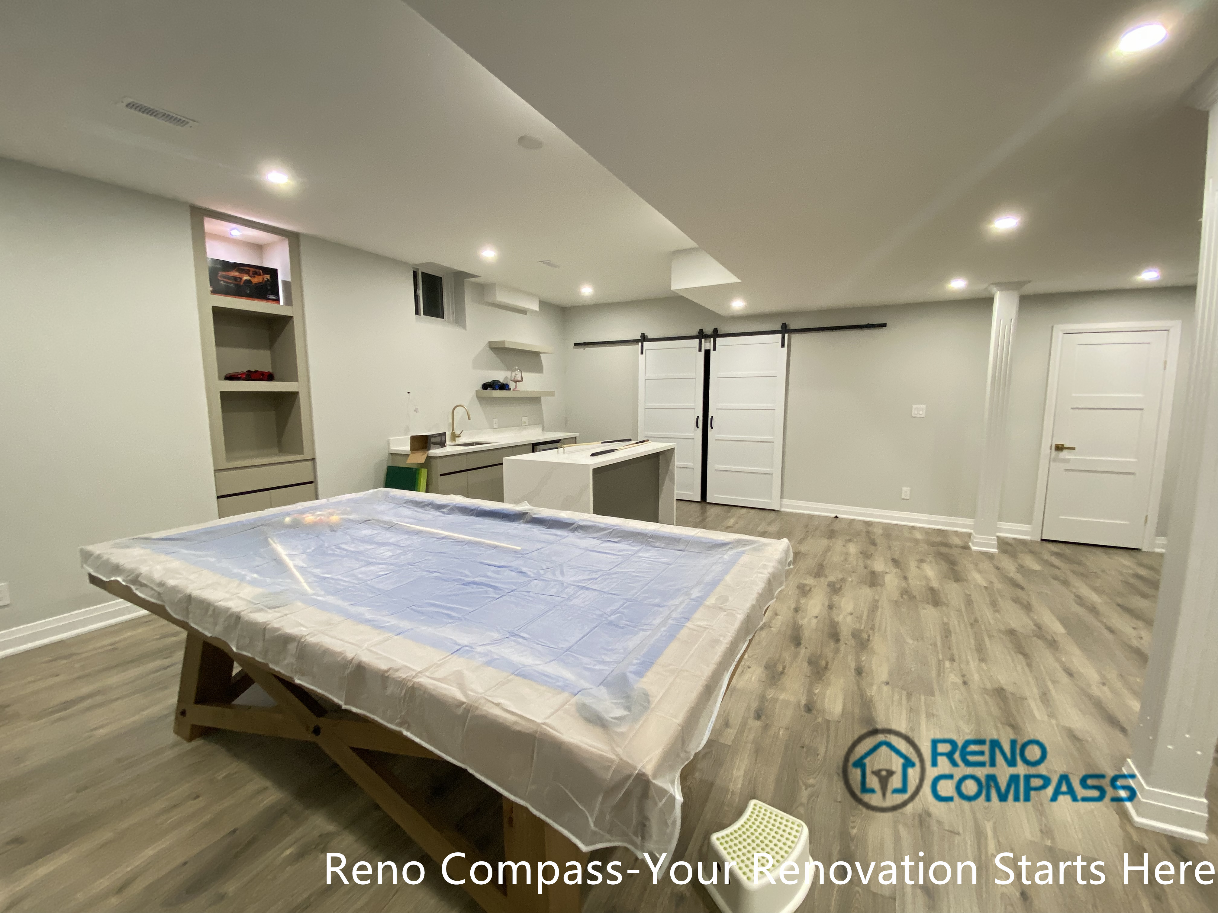 This Newmarket basement renovation showcases a spacious open-concept entertainment area with durable wood-look flooring, recessed ceiling lighting, and custom built-in cabinetry. Designed by a trusted Toronto renovation company, the space is optimized for recreation, games, and family gatherings, offering flexibility for a pool table, bar area, or multi-functional basement living zone.