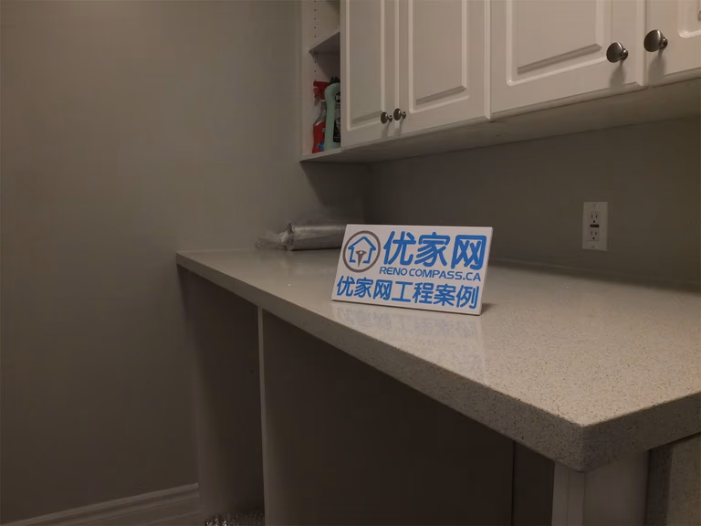 This Richmond Hill basement renovation highlights a detailed view of the utility area, featuring a quartz countertop, custom upper cabinets, and a built-in sink. The clean finishes and practical layout provide efficient storage and workspace, ideal for laundry or additional household use.
