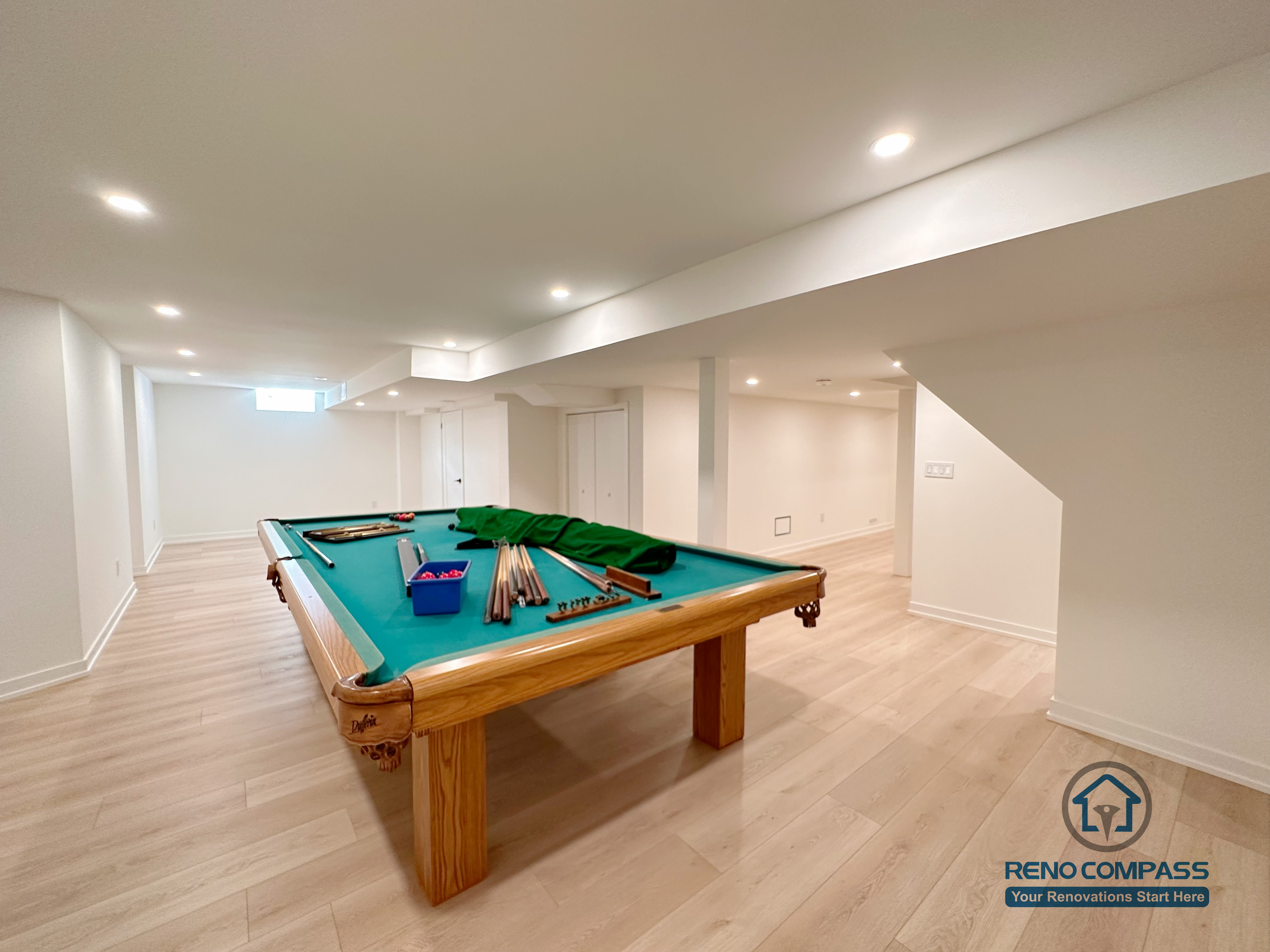 This Markham basement renovation showcases a spacious entertainment area designed for recreation and family gatherings. The open layout comfortably accommodates a full-size pool table, supported by wide-plank flooring, recessed ceiling lighting, and clean white finishes. Structural beams and columns are carefully integrated to preserve ceiling height and visual openness. Completed by an experienced Toronto renovation company, Reno Compass Inc., this basement design demonstrates how functional planning can transform unused space into a versatile entertainment zone for everyday living.