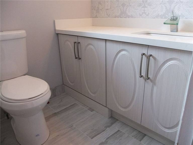 This bathroom renovation features a clean vanity installation positioned beside a window to maximize natural light and everyday visibility. The white cabinet design, paired with a smooth countertop and neutral wall finishes, creates a bright and comfortable atmosphere. Careful spacing between fixtures improves circulation and usability in the bathroom layout. Completed by a trusted Toronto renovation company, this project reflects attention to detail, balance, and functional design.