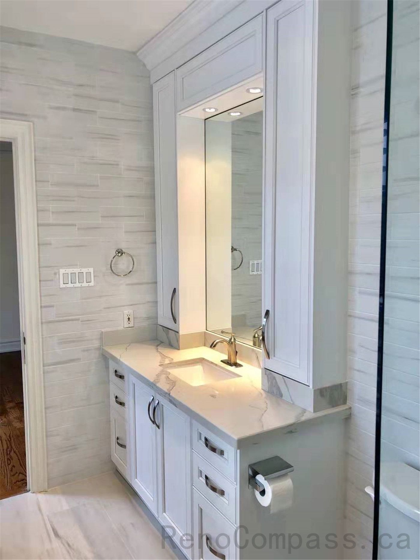 This North York bathroom renovation features a modern glass shower enclosure with marble-look wall tiles, a custom vanity with quartz countertop, and coordinated brushed metal fixtures. The bright layout enhances space, functionality, and everyday comfort while maintaining a clean contemporary style. Completed by a professional Toronto renovation company focused on quality craftsmanship and refined bathroom design.