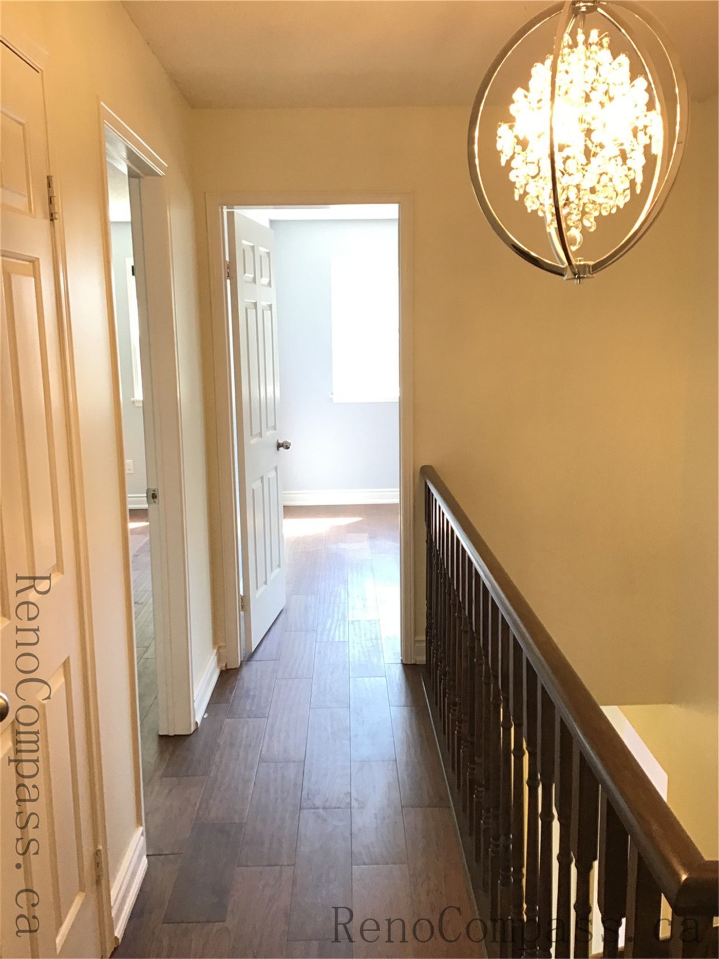 This image showcases a renovated hallway in a Richmond Hill interior project, featuring warm-toned flooring, clean white doors, and a modern pendant light fixture. The design enhances brightness and flow, creating a comfortable and cohesive transition space.