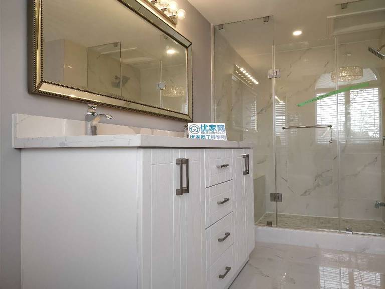 This modern bathroom renovation in Ajax features a double sink vanity with quartz countertop, a large framed mirror with upgraded lighting, and a glass-enclosed walk-in shower. The clean layout and premium materials create a spa-like atmosphere while improving daily functionality. As part of a full house renovation, this bathroom design combines elegance, durability, and modern comfort.