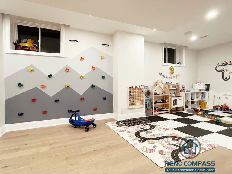 Basement playroom renovation in Newmarket featuring a custom climbing wall, soft play flooring, built-in storage, and an open layout designed for children’s activity and creative play.