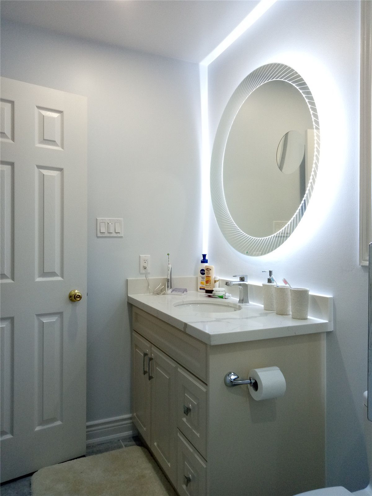 This image showcases a renovated bathroom vanity as part of a Richmond Hill basement and upper floor bathroom renovation project. The space features a modern vanity cabinet, updated countertop, and a round LED backlit mirror that enhances lighting and visual depth. Clean finishes and efficient layout improve both functionality and aesthetics, reflecting the attention to detail and craftsmanship of a professional Toronto renovation company.