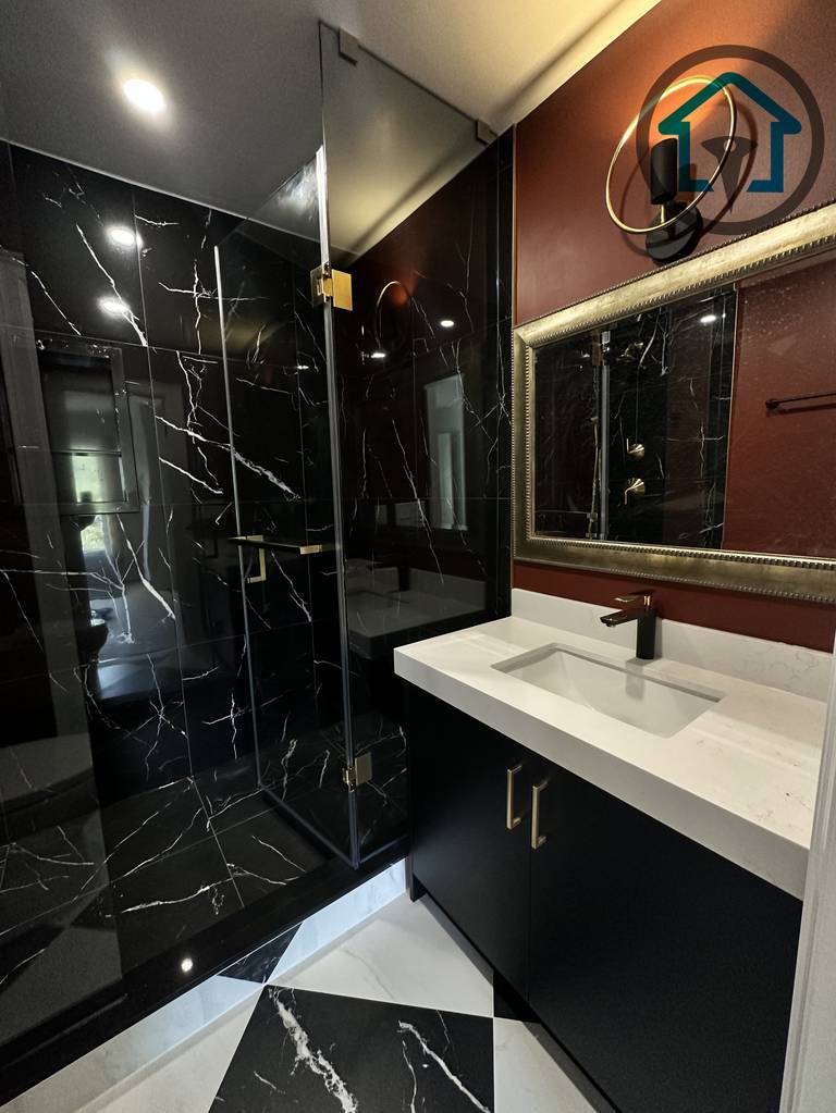 This modern powder room was completed as part of a North York interior renovation project, featuring a sleek black marble walk-in shower, custom vanity cabinetry, and a bold contrast between dark stone surfaces and warm accent walls. Clean glass panels, integrated lighting, and refined material selection enhance both functionality and visual impact, delivered by a professional Toronto renovation company experienced in full interior renovations.