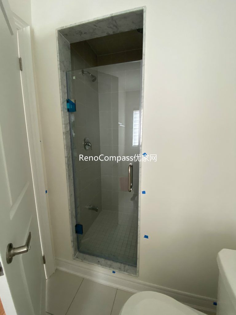 Modern bathroom remodel in Richmond Hill highlighting a frameless glass shower, bright white tiles, and updated fixtures completed by Reno Compass.