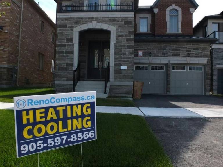 Professional outdoor air conditioner condenser installation by Reno Compass in Toronto. This energy-efficient HVAC unit is securely mounted on a raised stand with proper drainage and ventilation clearance, ensuring optimal cooling performance, durability, and safe operation for residential homes. Installed by licensed technicians for long-term reliability and comfort.