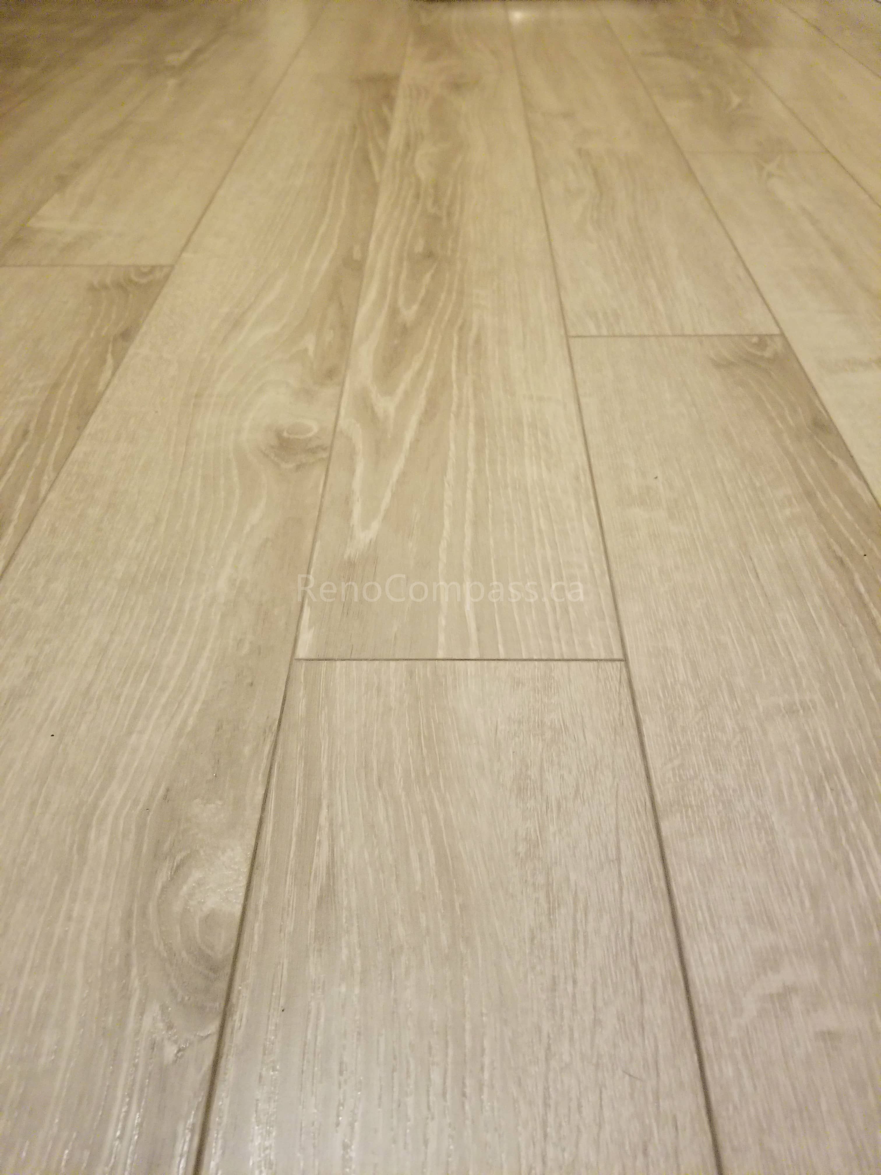 This Toronto basement renovation showcases newly installed light wood flooring paired with clean white baseboards for a modern and elegant finish. The durable laminate flooring enhances brightness and creates a warm, contemporary look while providing easy maintenance for basement living spaces. Installed by Reno Compass Inc., this flooring upgrade adds both style and functionality to the newly renovated basement interior.