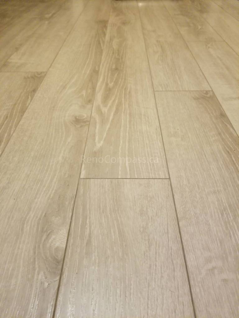 This Toronto basement renovation showcases newly installed light wood flooring paired with clean white baseboards for a modern and elegant finish. The durable laminate flooring enhances brightness and creates a warm, contemporary look while providing easy maintenance for basement living spaces. Installed by Reno Compass Inc., this flooring upgrade adds both style and functionality to the newly renovated basement interior.