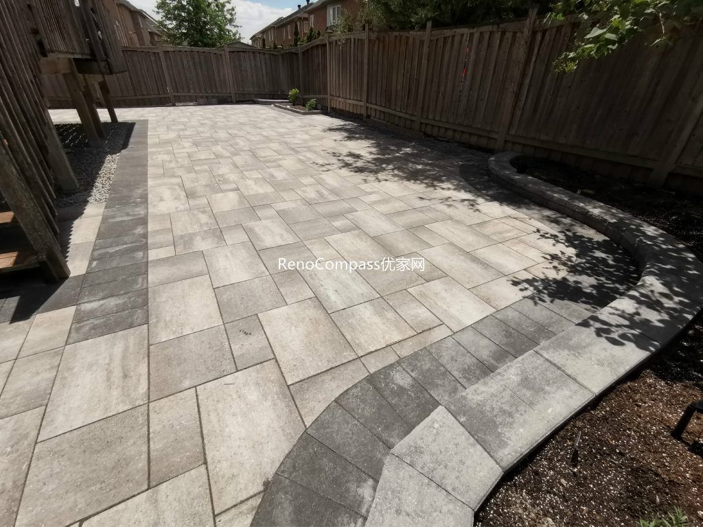 Backyard interlocking patio project in Richmond Hill designed around a wooden deck. Featuring clean, neutral-toned stones arranged for durability and aesthetic appeal — a perfect balance of function and style by Reno Compass.