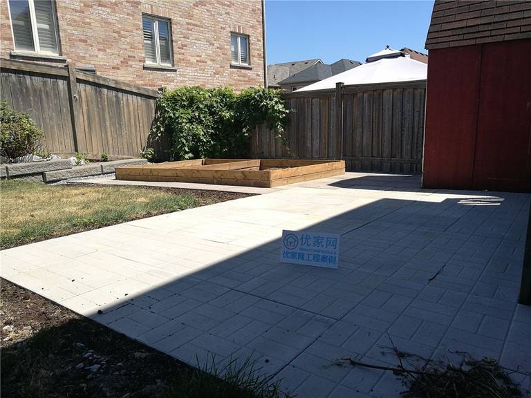 A completed backyard interlock patio in Vaughan featuring light-colored concrete pavers that create a clean, spacious, and low-maintenance outdoor living area. The interlocking stone surface seamlessly integrates with raised garden beds and surrounding lawn, enhancing drainage, usability, and overall backyard aesthetics. This project showcases professional landscaping and interlock installation services in Vaughan.