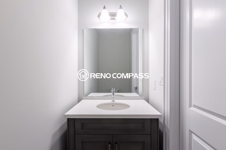 Simple and elegant powder room renovation in Newmarket featuring a modern vanity cabinet, quartz countertop, wall mirror and contemporary lighting fixture. Completed by a professional Toronto renovation company, this compact bathroom design maximizes space while maintaining a clean and stylish look.
