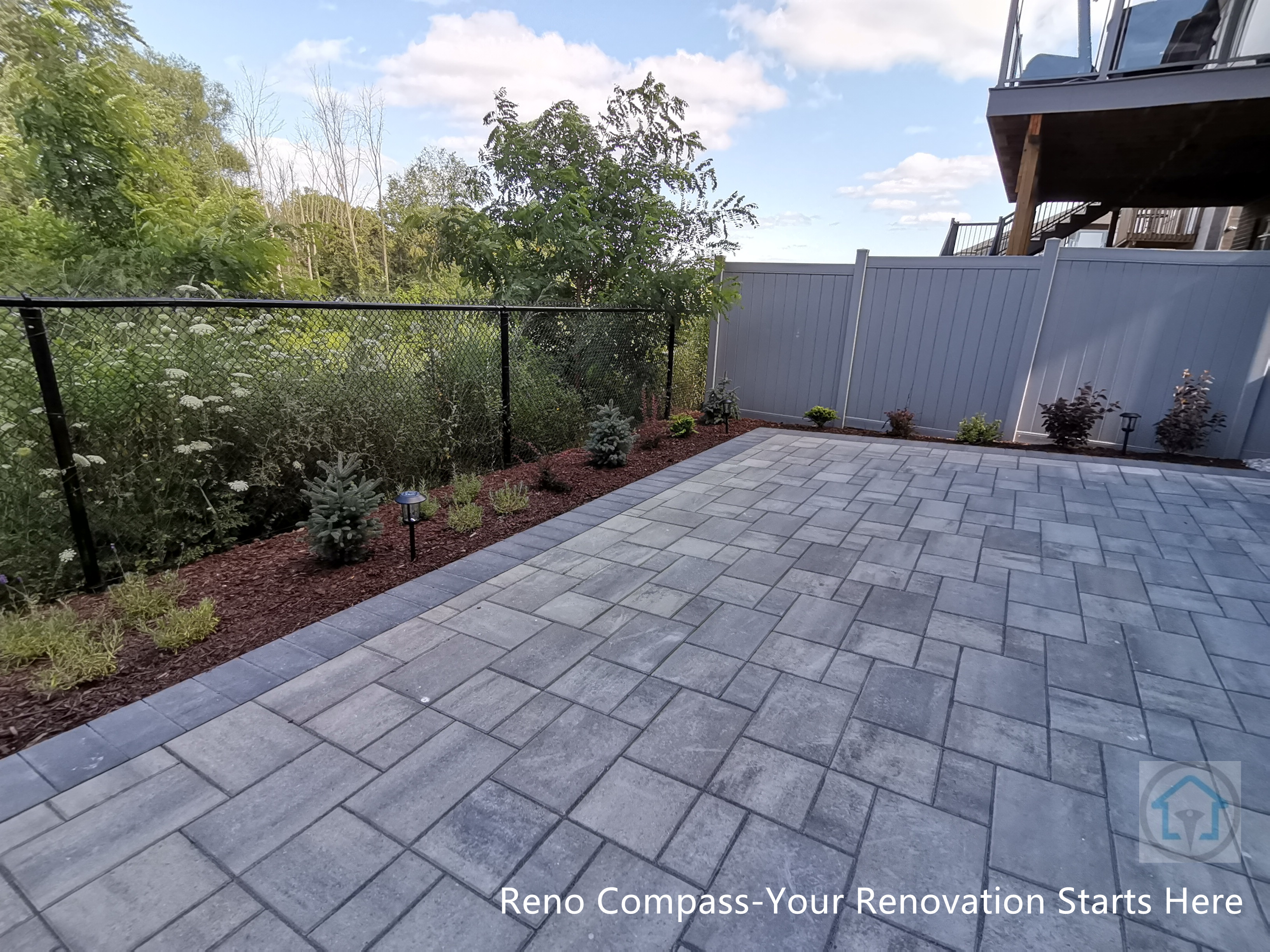 This Vaughan backyard patio renovation features a spacious interlocking stone paver layout designed for outdoor relaxation and entertaining. The clean stone pattern, defined borders, and integrated landscaping create a durable, low-maintenance patio that blends seamlessly with the natural surroundings and backyard fencing.
