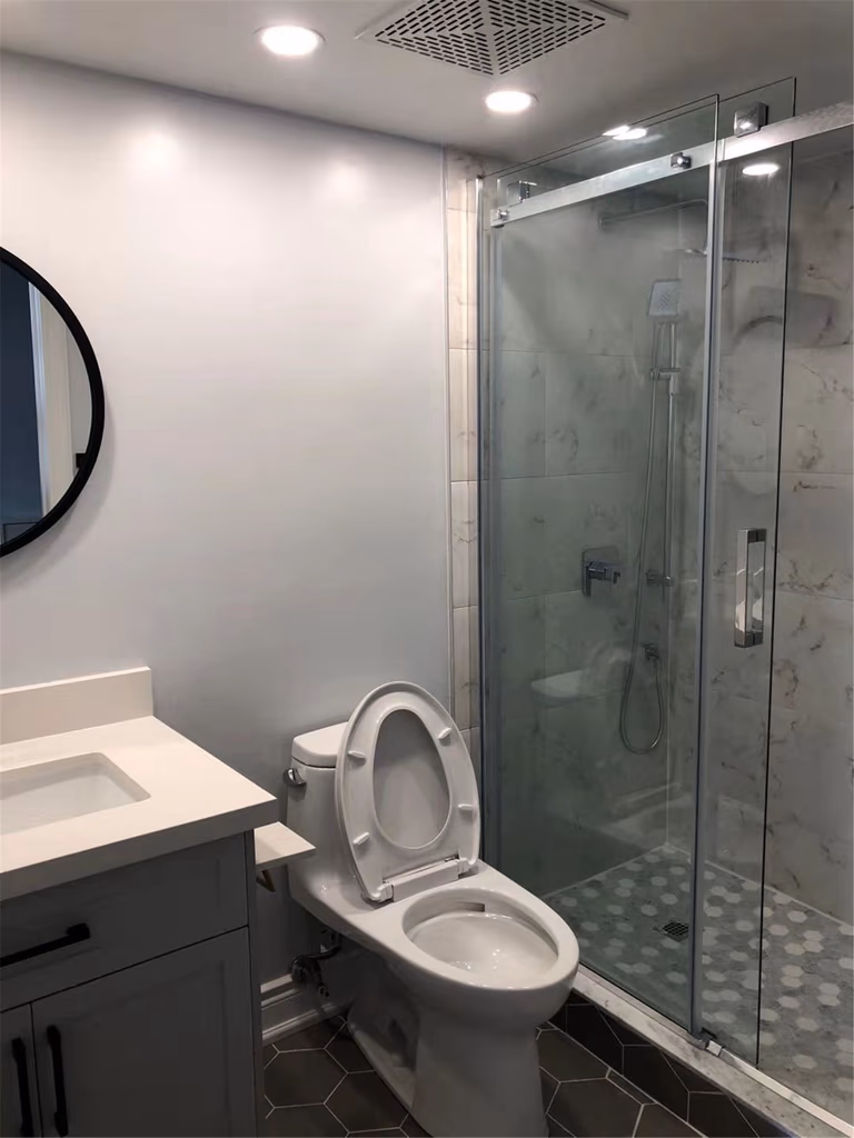 This Richmond Hill bathroom renovation features a sleek glass-enclosed shower, modern vanity with quartz countertop, and updated tile flooring for a clean and functional design. Recessed lighting, ventilation upgrades, and contemporary fixtures enhance comfort and usability. Completed by an experienced Toronto renovation company, this bathroom transformation delivers a bright, efficient space with long-lasting materials and a timeless modern look.