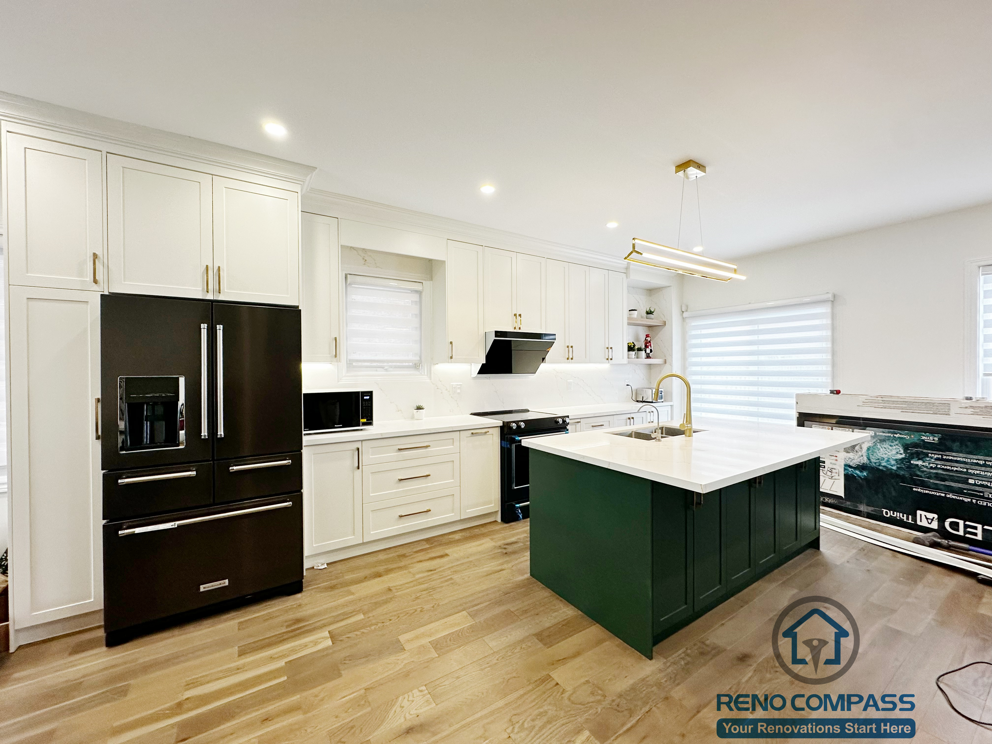 Interior renovation in Markham showcasing a modern kitchen with custom white cabinetry, a contrasting dark green island, quartz countertops, and integrated lighting. The open layout enhances functionality, flow, and everyday family use.