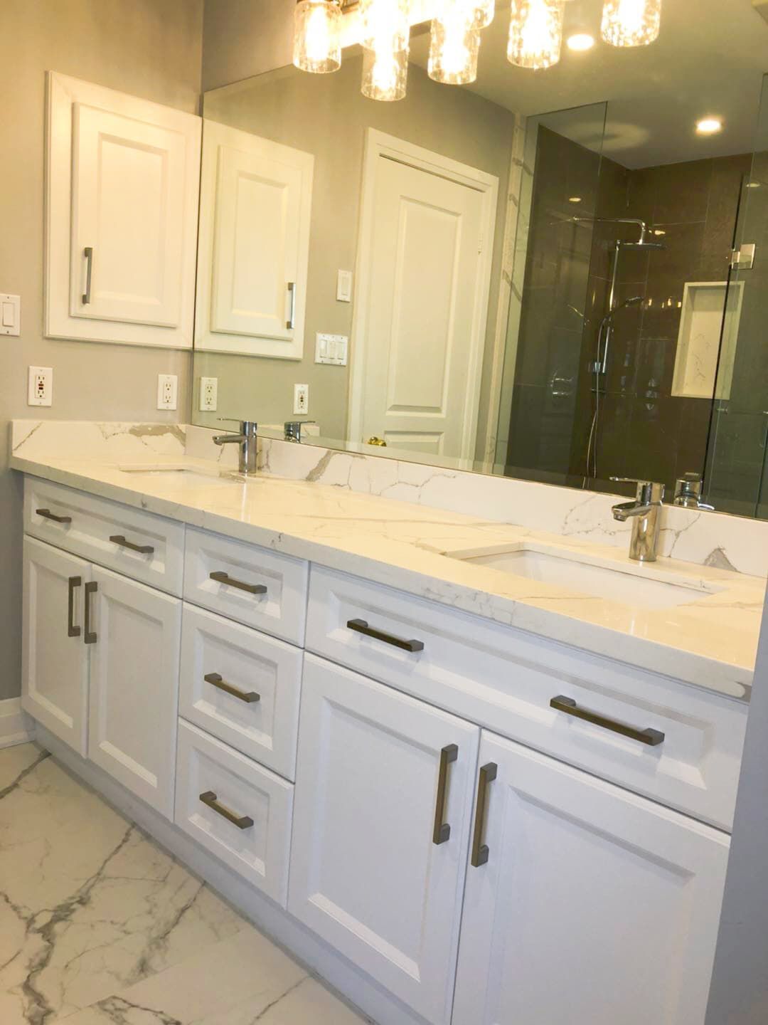This Richmond Hill bathroom renovation features a modern double-sink vanity with custom white shaker cabinetry, quartz countertops, and sleek black hardware. The upgraded layout improves both storage and daily functionality while maintaining a clean and timeless aesthetic. Large-format marble-style flooring and a glass shower enclosure enhance the luxury feel, creating a bright and elegant space ideal for modern family living. Professionally completed by a trusted Toronto renovation company, this project combines durability, comfort, and refined design for long-term use.